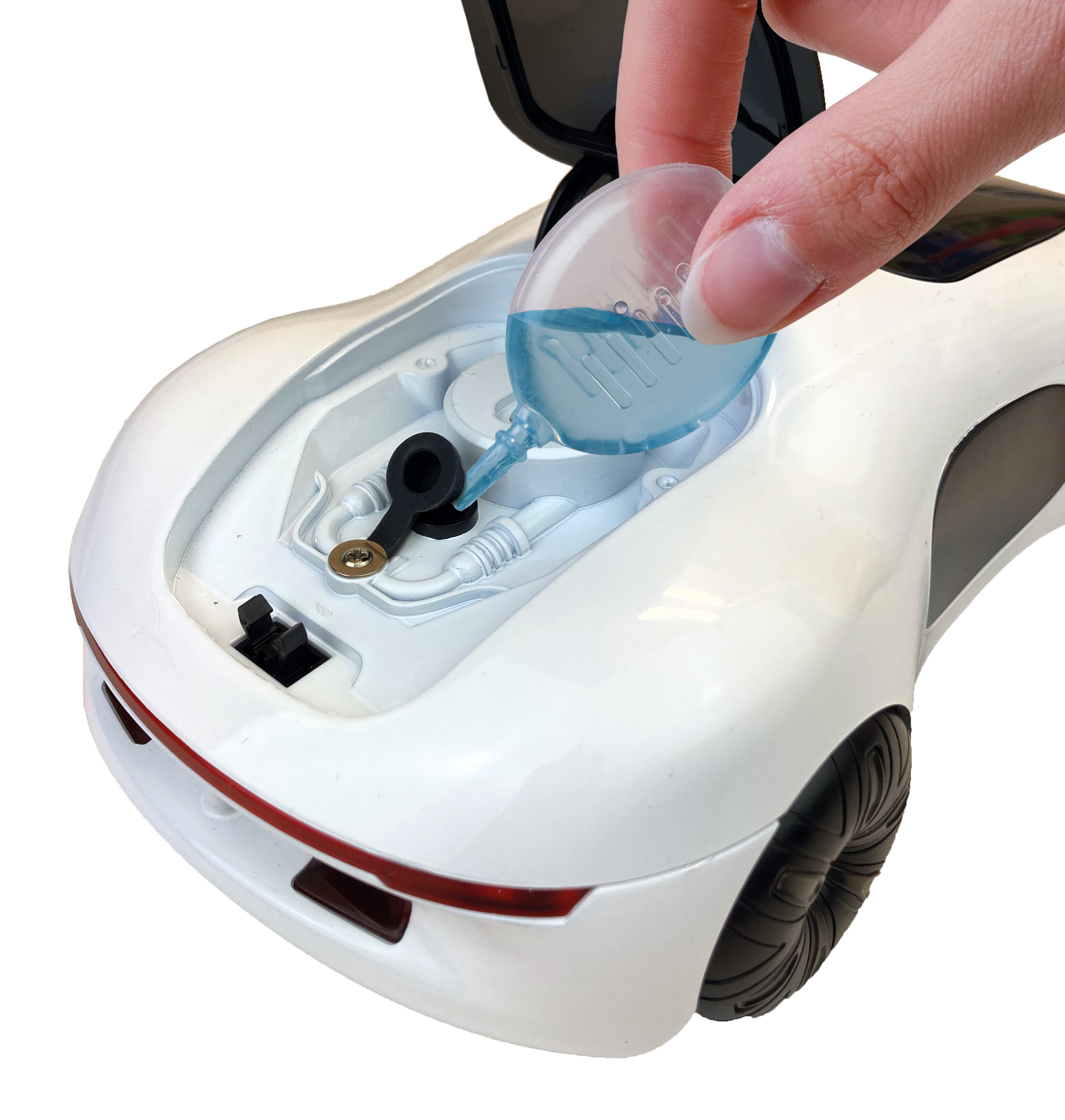 Eine Hand, die blaue Flüssigkeit in den Motorraum eines weißen Spielzeugautos gießt. Das Auto ist weiß mit schwarzen Reifen.