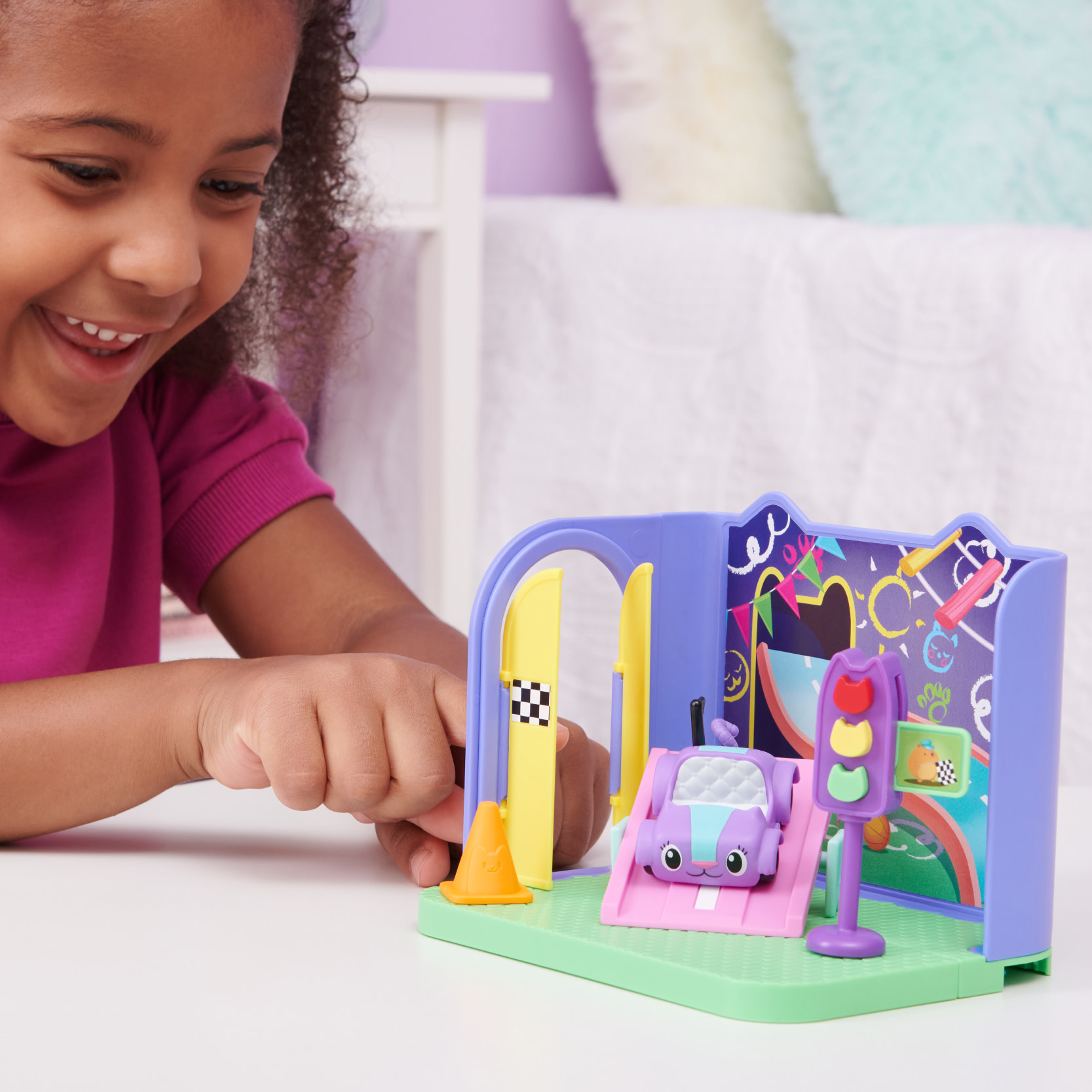 Ein Mädchen spielt mit einem Spielzeug-Spielset. Das Spielset hat eine Straße, ein Auto und eine Ampel.