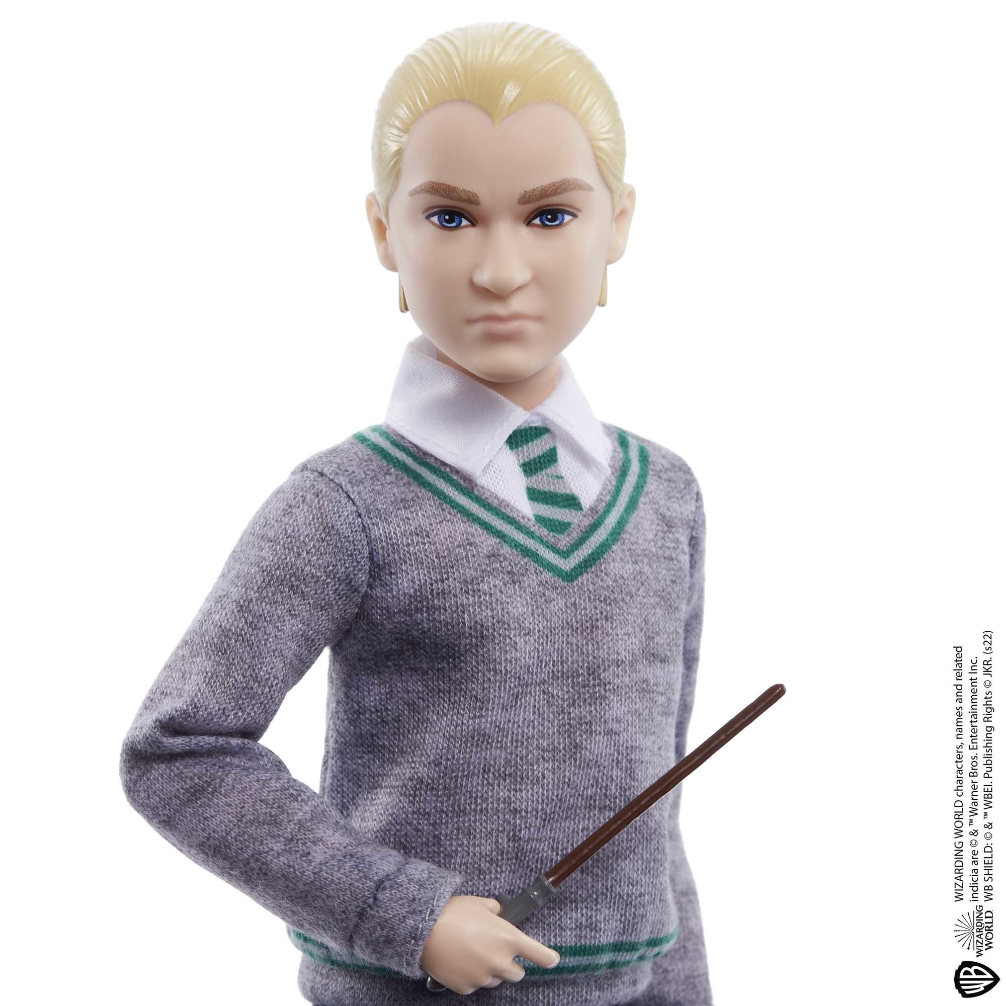 Lalka Draco Malfoy z blond włosami i różdżką. Ma na sobie szary sweter.