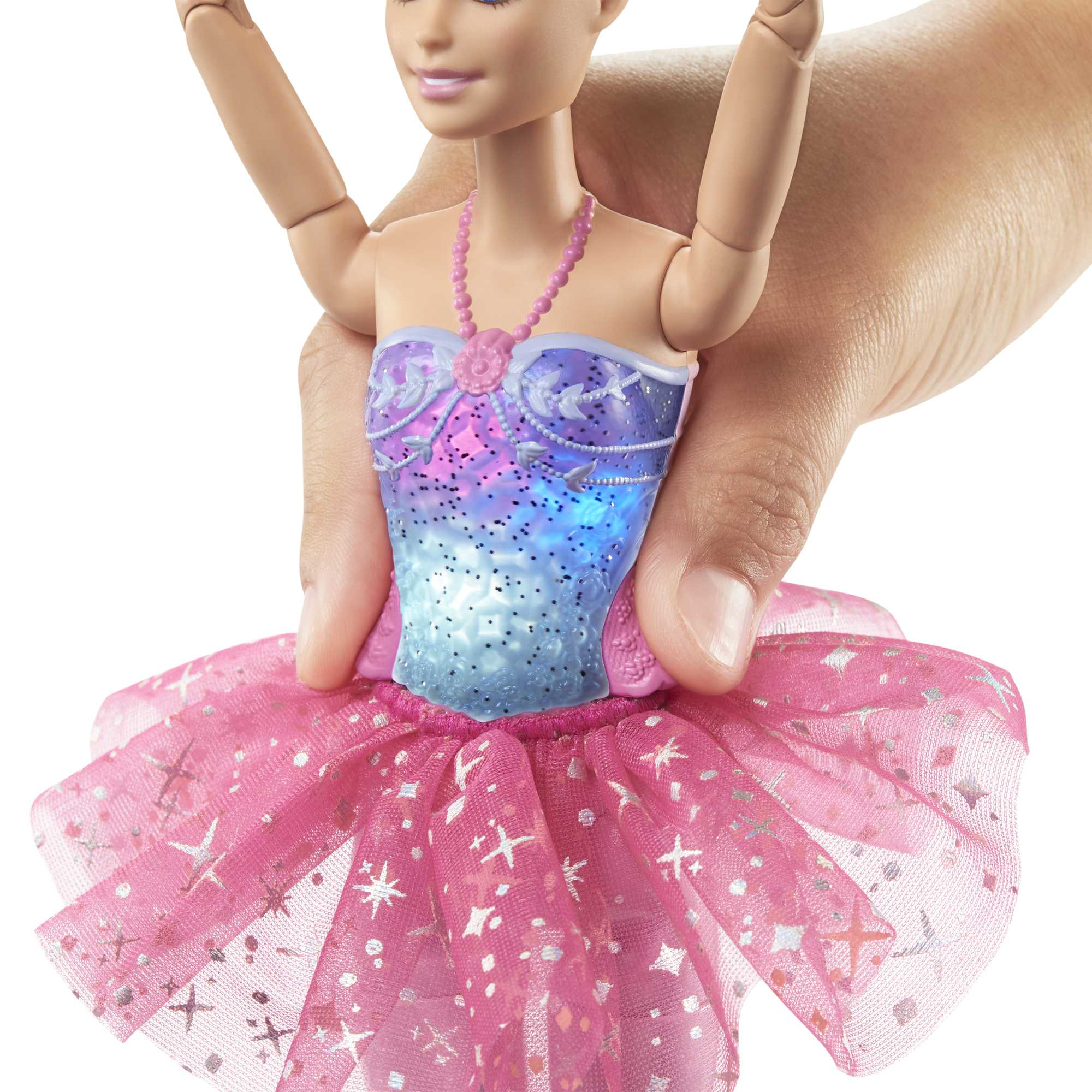 Eine Puppe mit rosa Tutu und blau-lila Oberteil wird von einer Hand gehalten, Nahaufnahme.