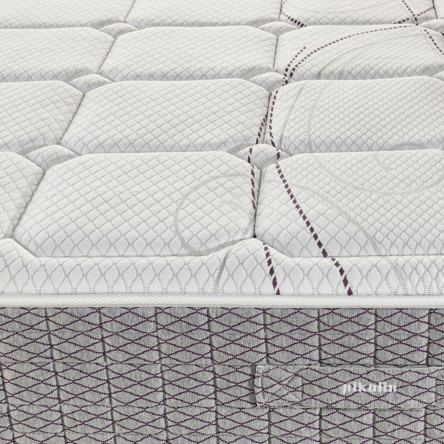 Primer plano de un colchón blanco con patrón de diamantes y borde gris.