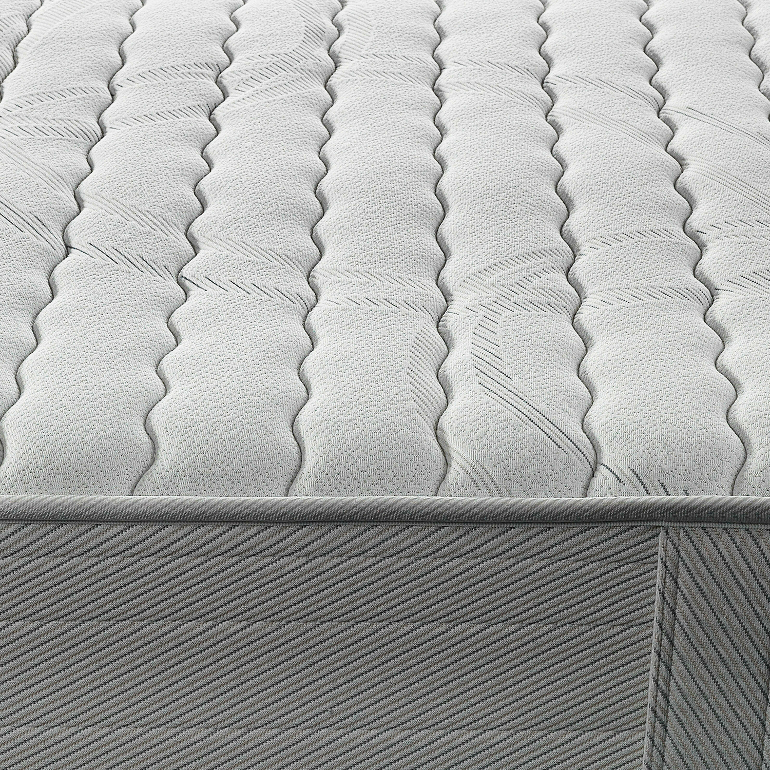 Primer plano de una superficie de colchón blanco, con patrón de costura ondulado y borde gris.