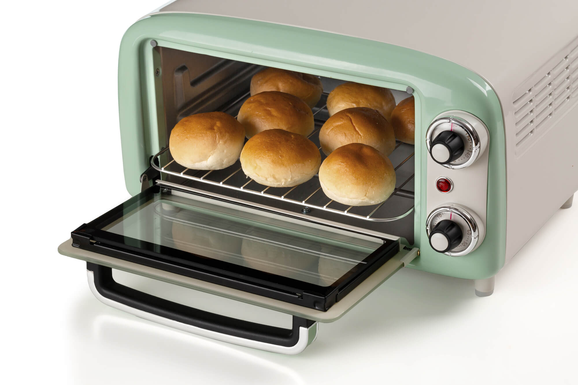 Otwarty, miętowo-zielony i biały piekarnik w stylu retro z pieczonymi bułkami na ruszcie.
