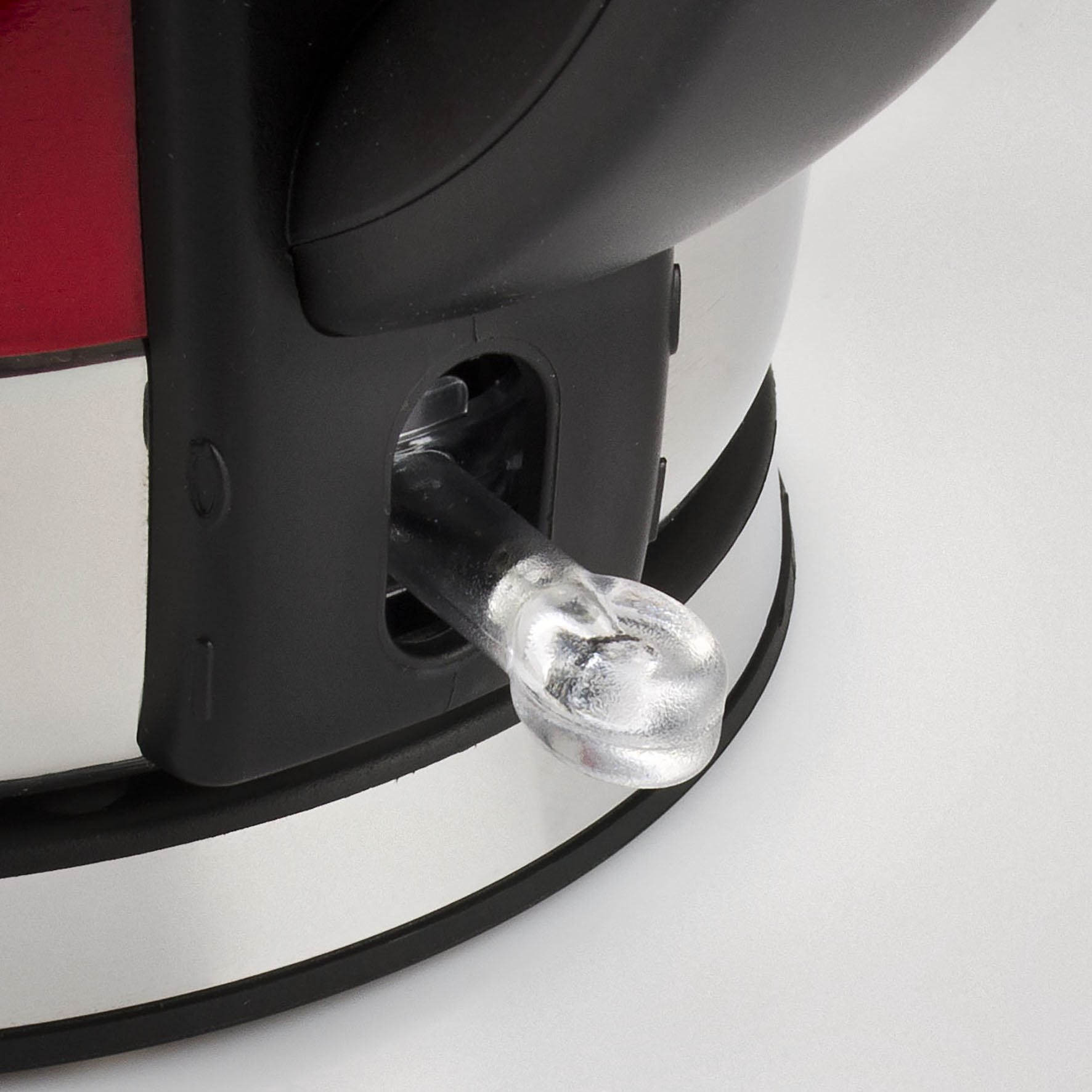 Zbliżenie czerwonego czajnika elektrycznego z czarnym uchwytem i przezroczystym przyciskiem zasilania.