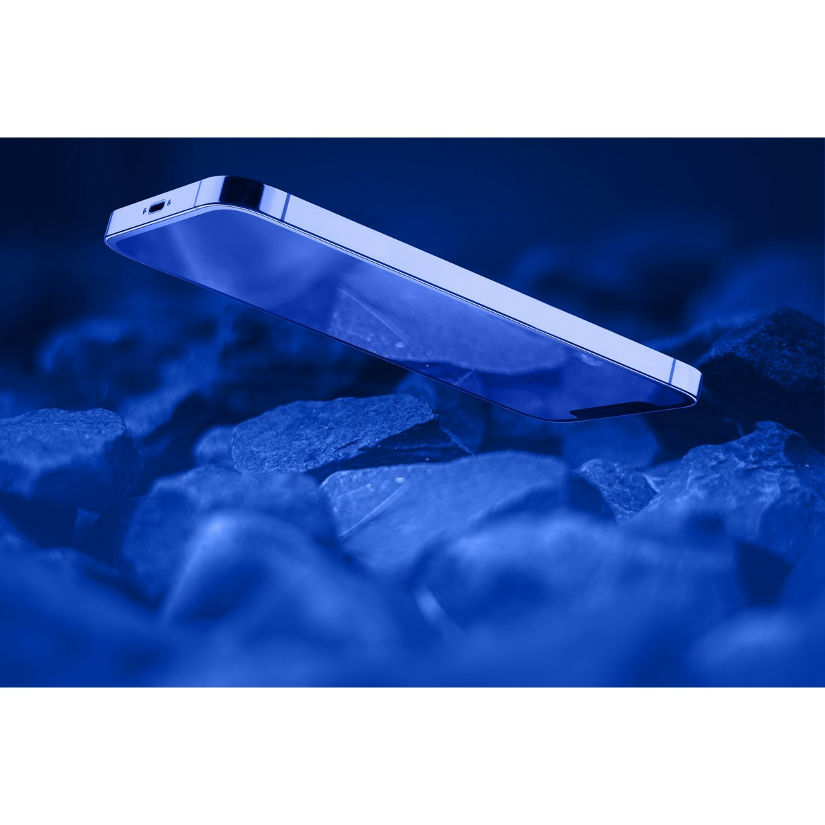 Uno smartphone con tinta blu è posizionato su un mucchio di rocce blu. Il telefono è leggermente inclinato.