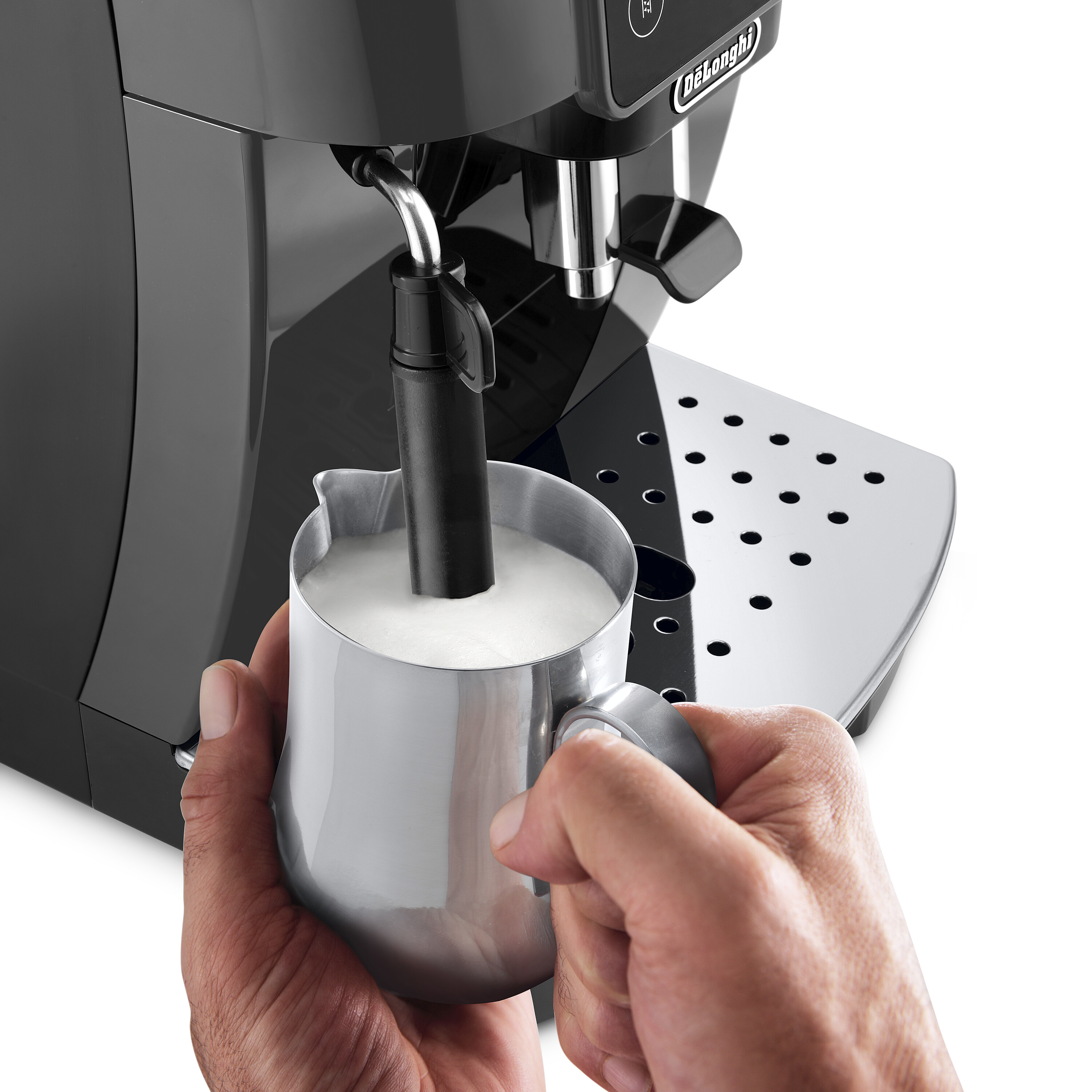 Le mani di una persona che tiene un boccale di metallo mentre schiuma il latte.