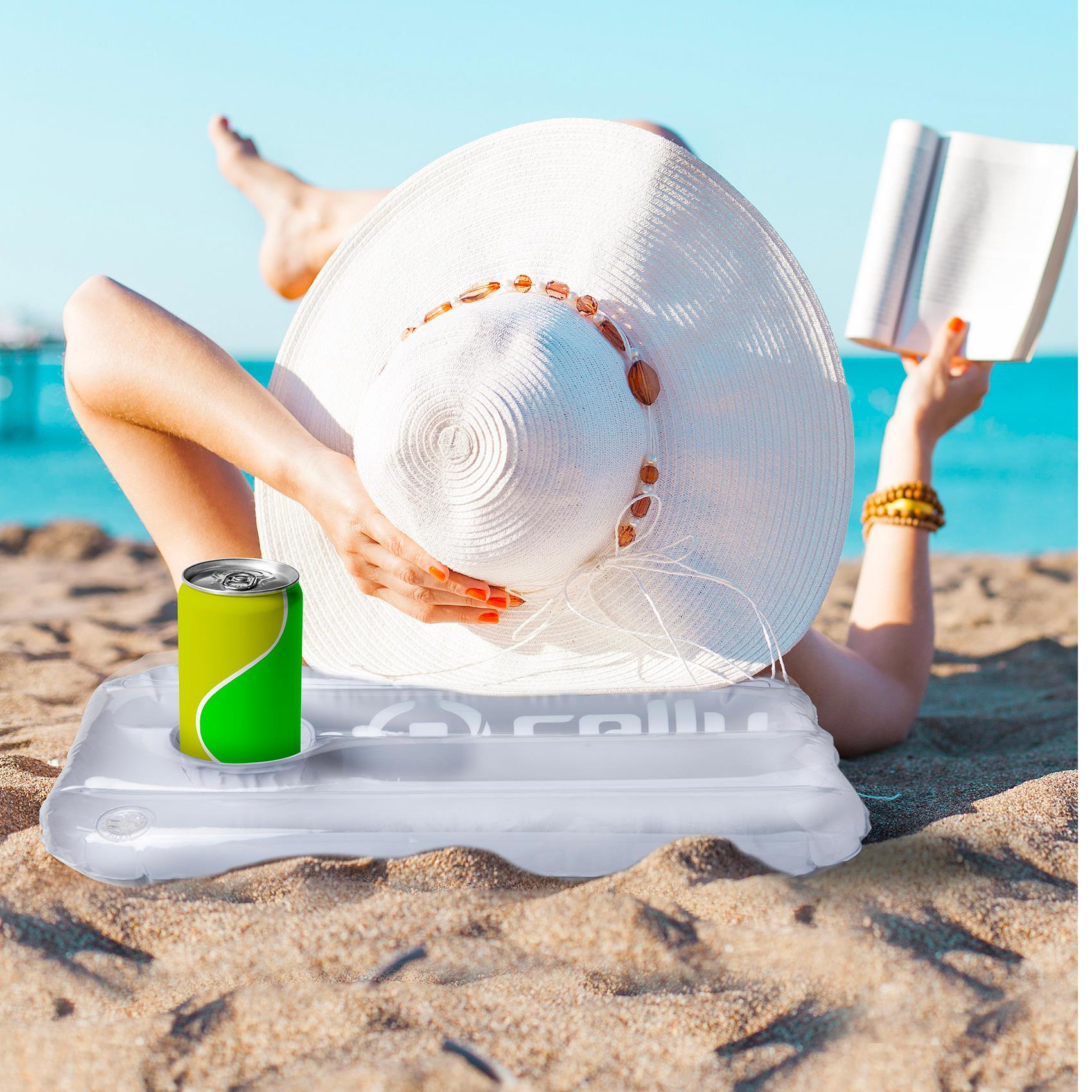 Osoba czytająca książkę na plaży podczas opalania, z napojem w pobliżu.