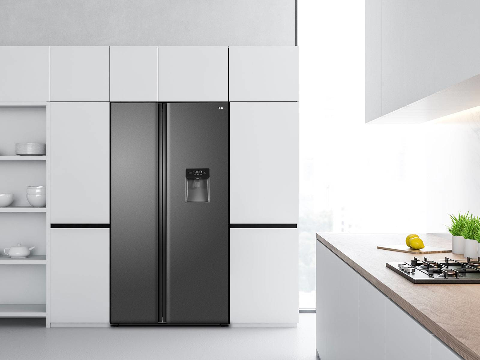 Un frigorifero grigio scuro in un ambiente cucina, accanto a mobili e bancone bianchi.