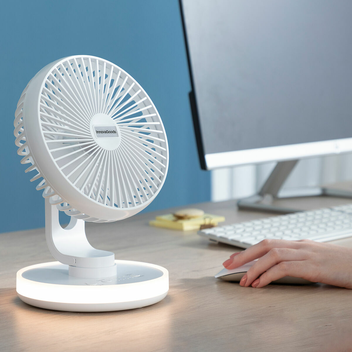 Weißer Tischventilator auf dem Tisch. Computer, Tastatur und Hand mit Maus im Hintergrund.