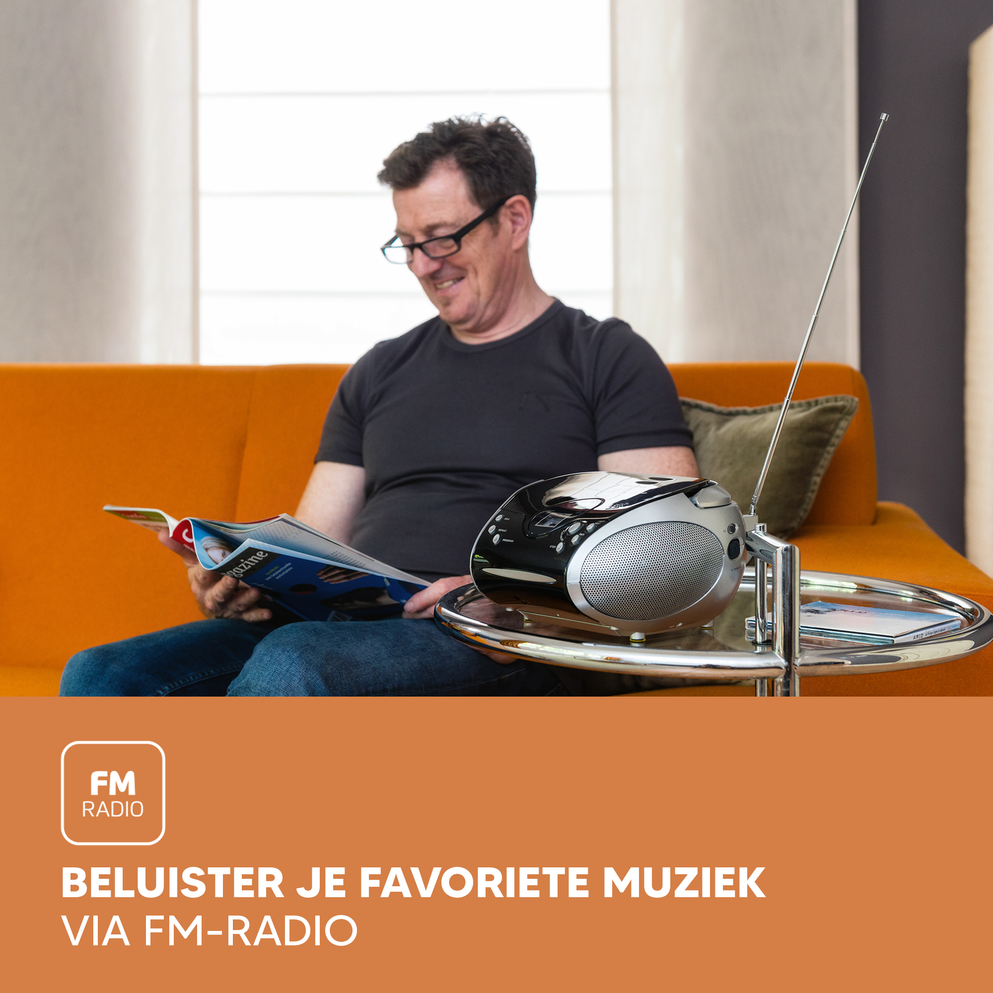 Man on orange sofa reading. Radio on table, FM radio text. Magazine and silver stand are visible.