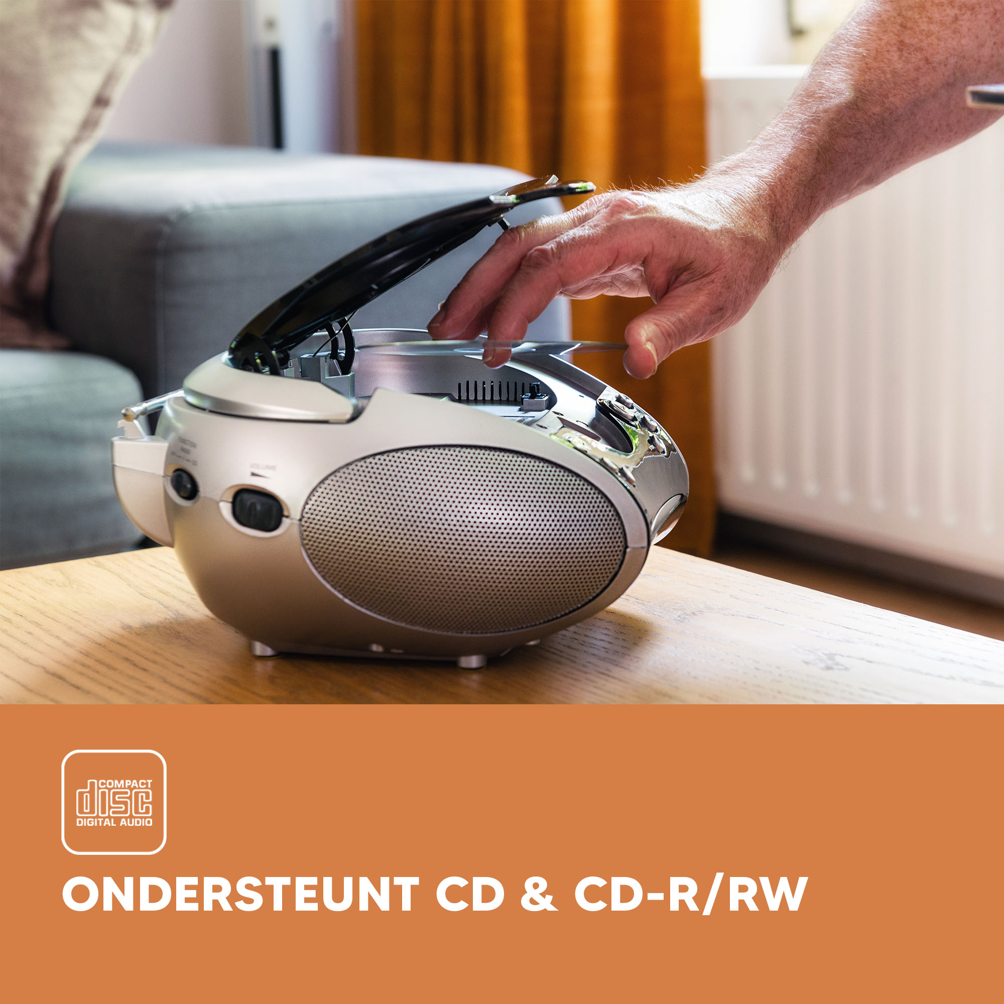 A person's hand is putting a CD into a silver, portable CD player.