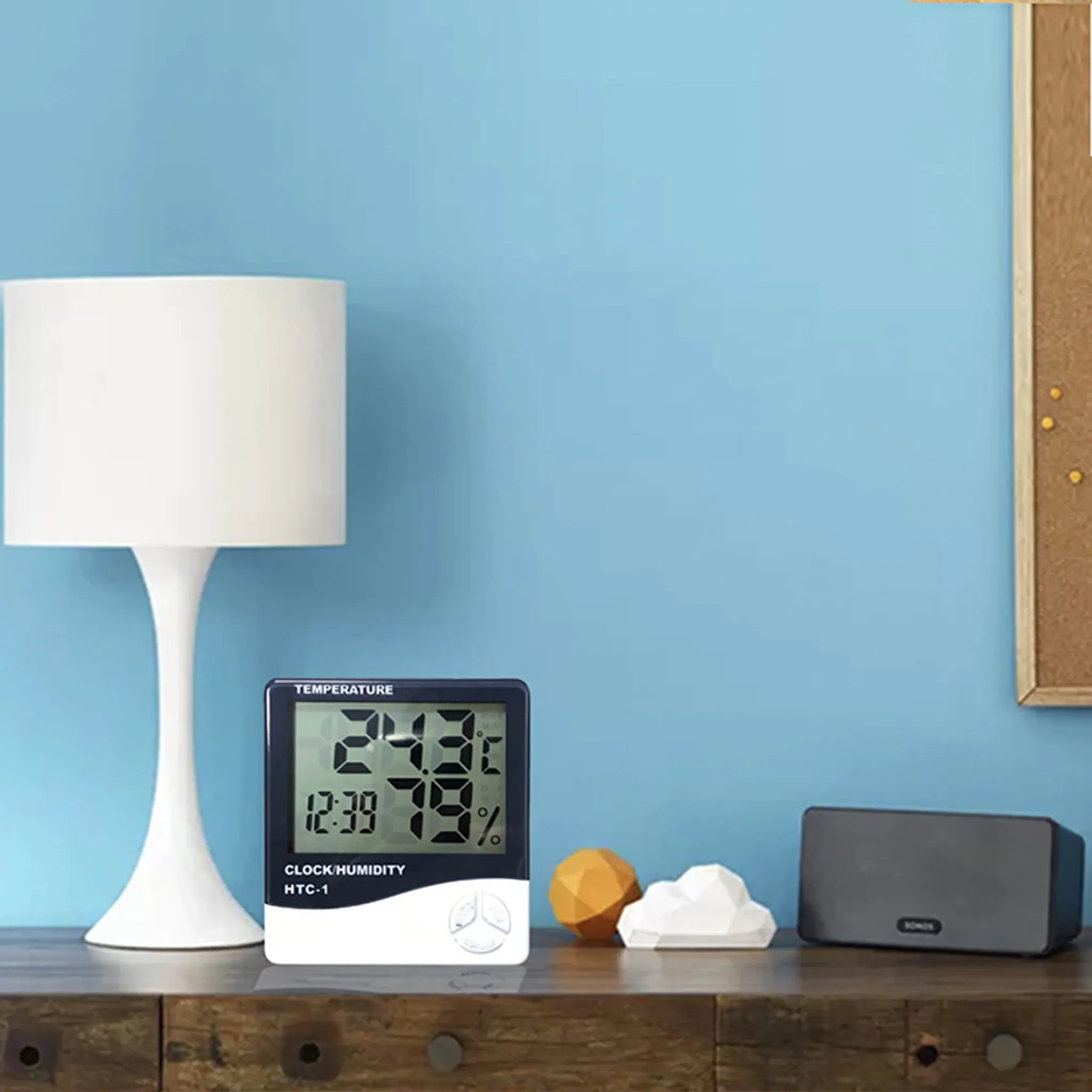 Digitales Thermometer und Dekoration auf Holzoberfläche, blauer Wand im Hintergrund.