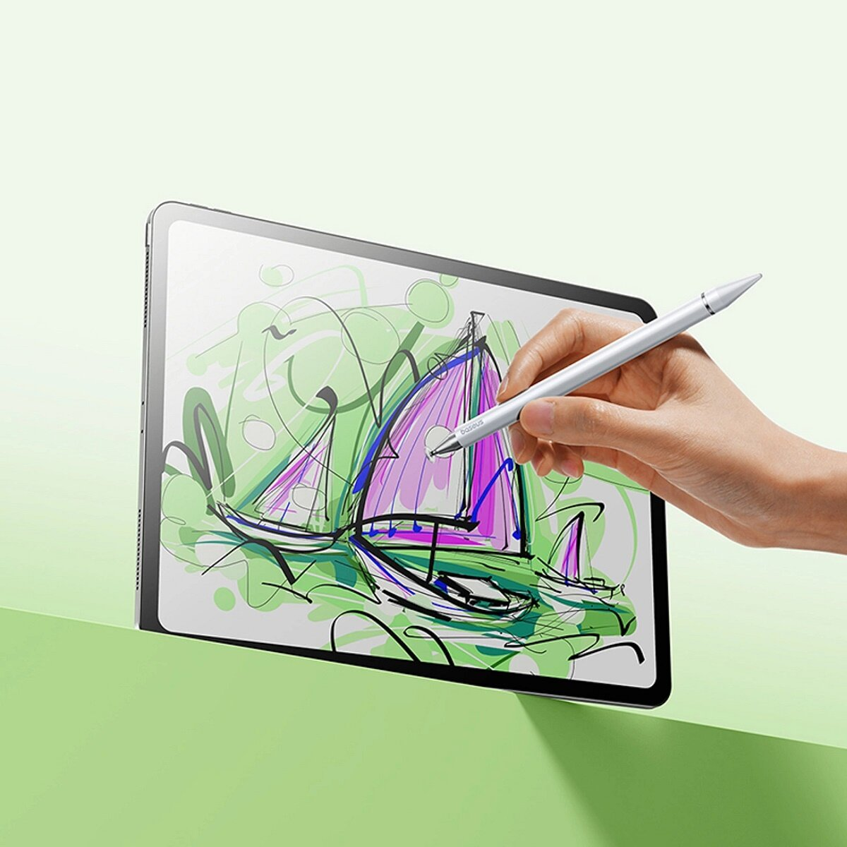 Tablet z rysunkiem na ekranie. Ręka trzymająca srebrny rysik. Zielone tło.