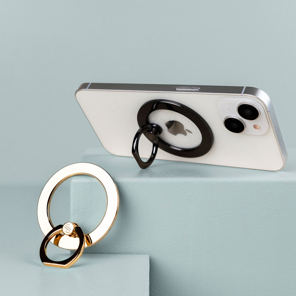 Witte telefoon met gouden ringhouder. Gouden ringhouder ernaast geplaatst.