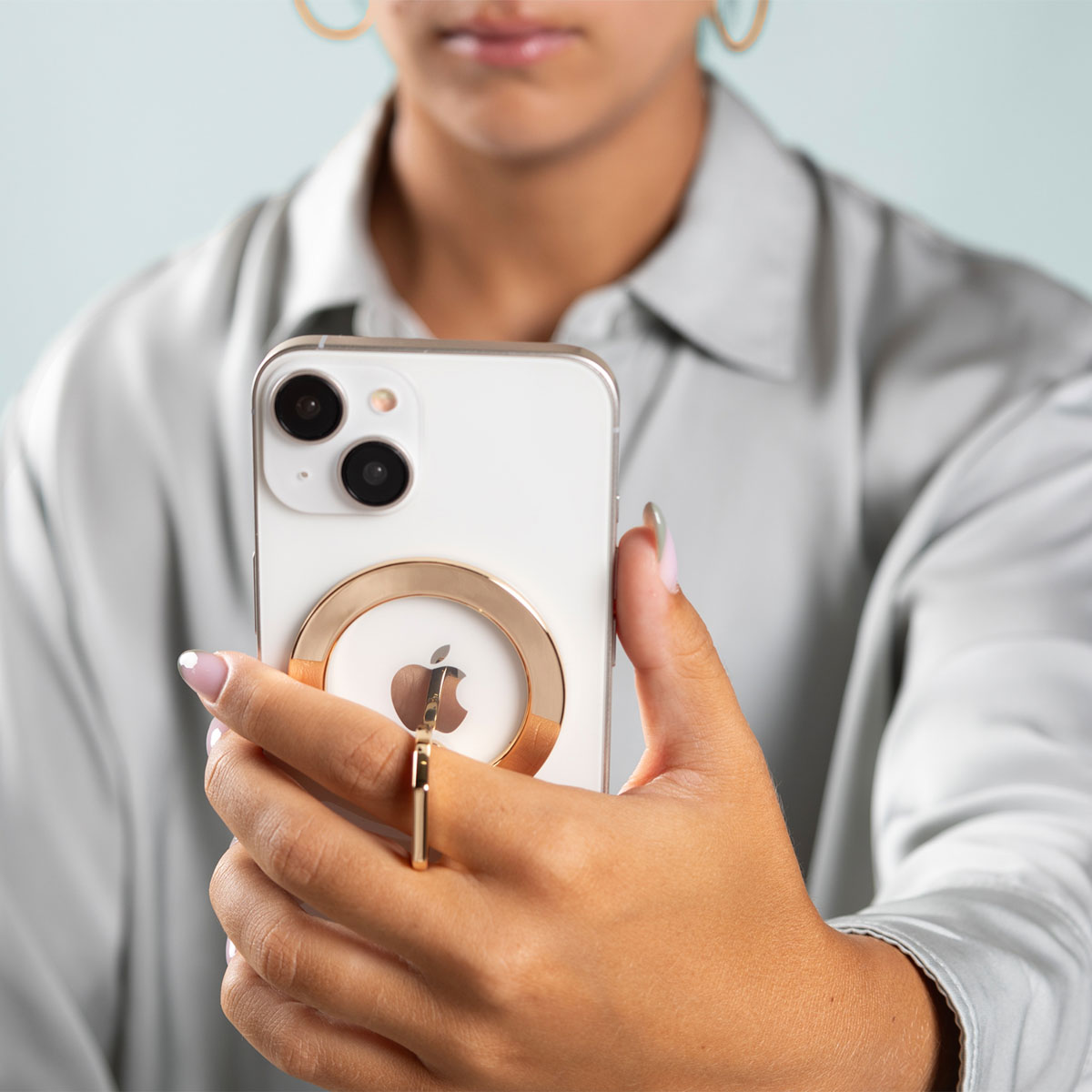 Een persoon die een witte iPhone vasthoudt met een gouden ring. De telefoon heeft een gouden ring op de achterkant.