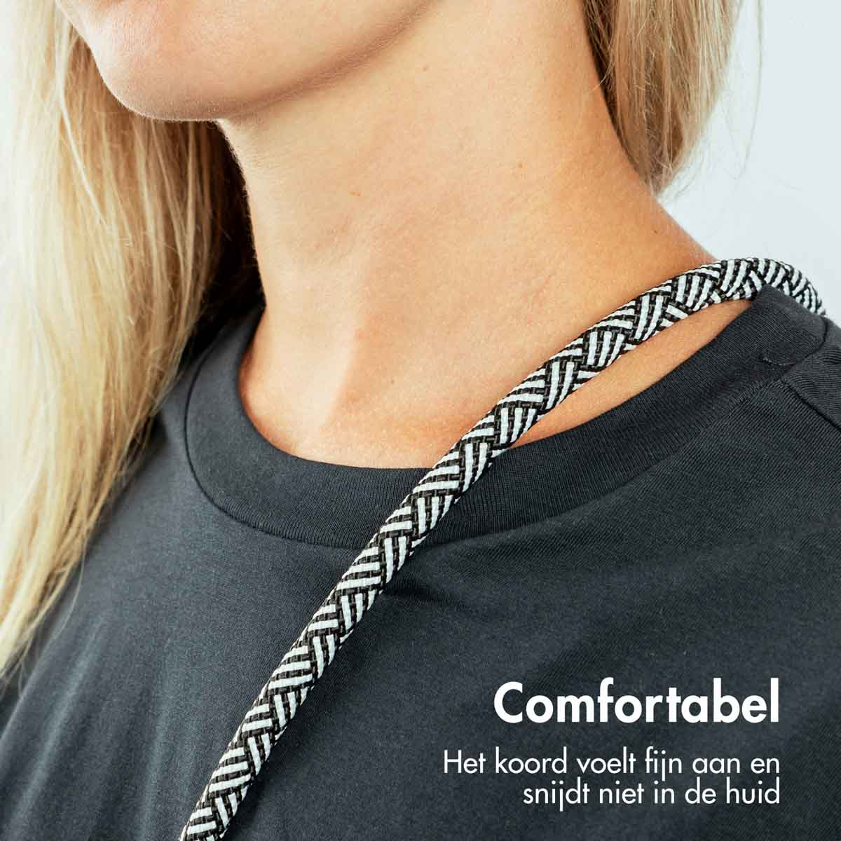 Een vrouw die een zwart shirt draagt met een zwart-wit patroonkoord om haar nek.