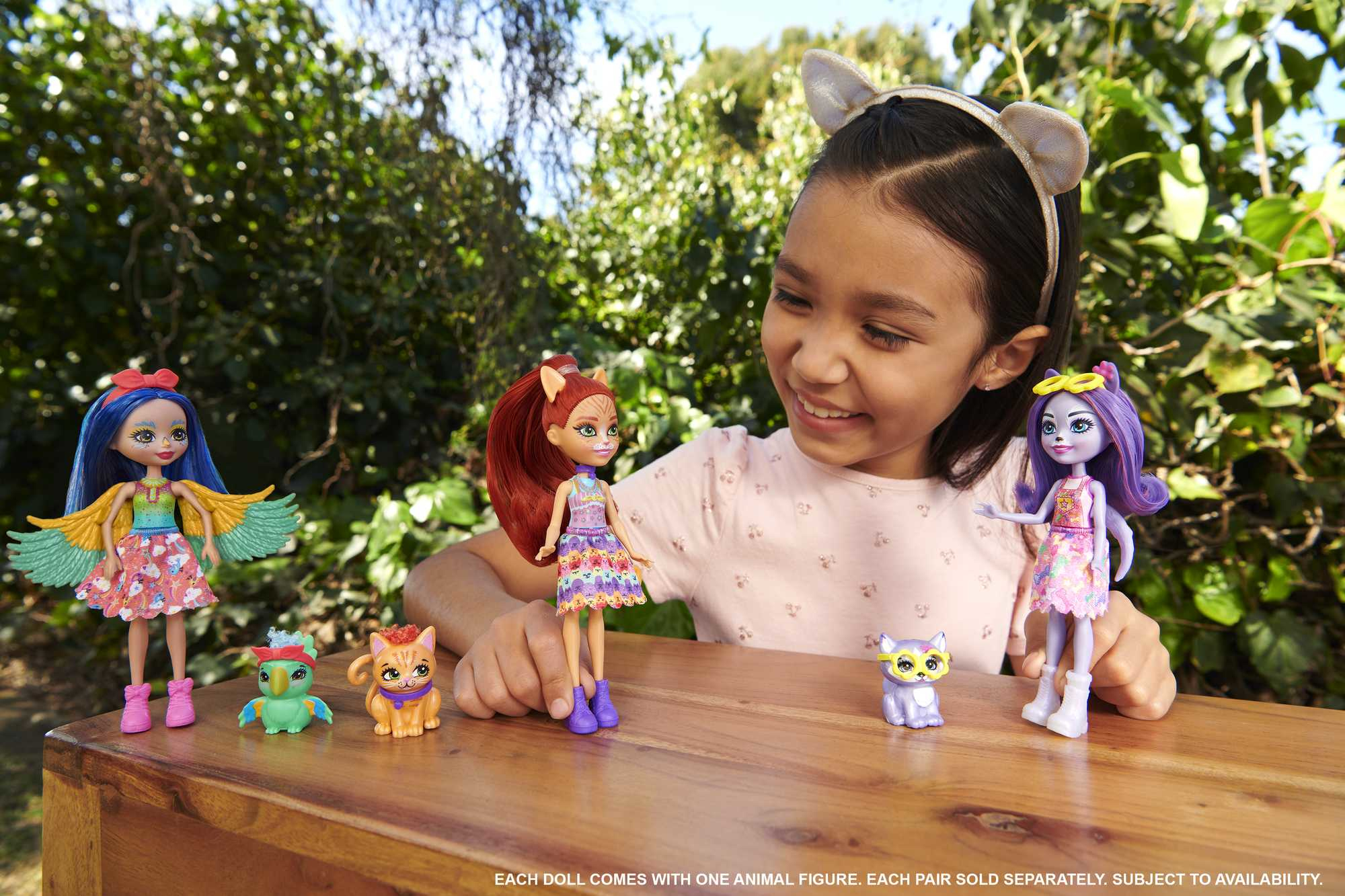 Niña sonriendo, sosteniendo muñecas y figuras de animales. Las muñecas tienen vestidos coloridos y accesorios temáticos de animales.