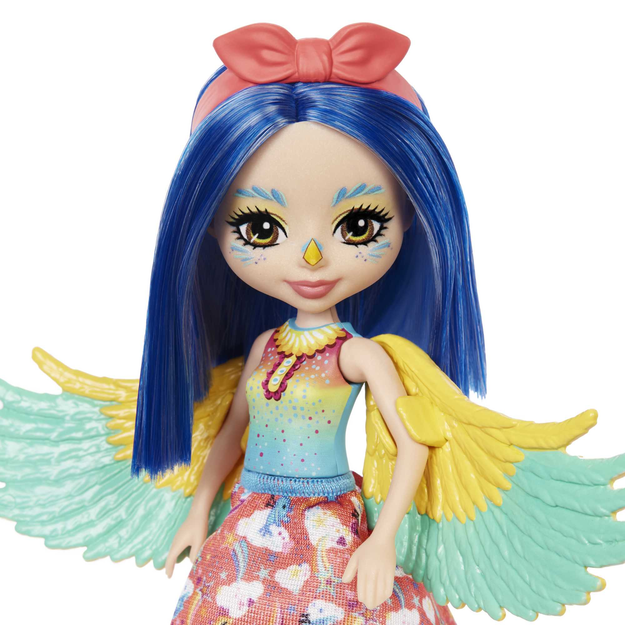 Una muñeca con cabello azul y alas. Lleva un atuendo colorido. Un lazo rosa en la cabeza.