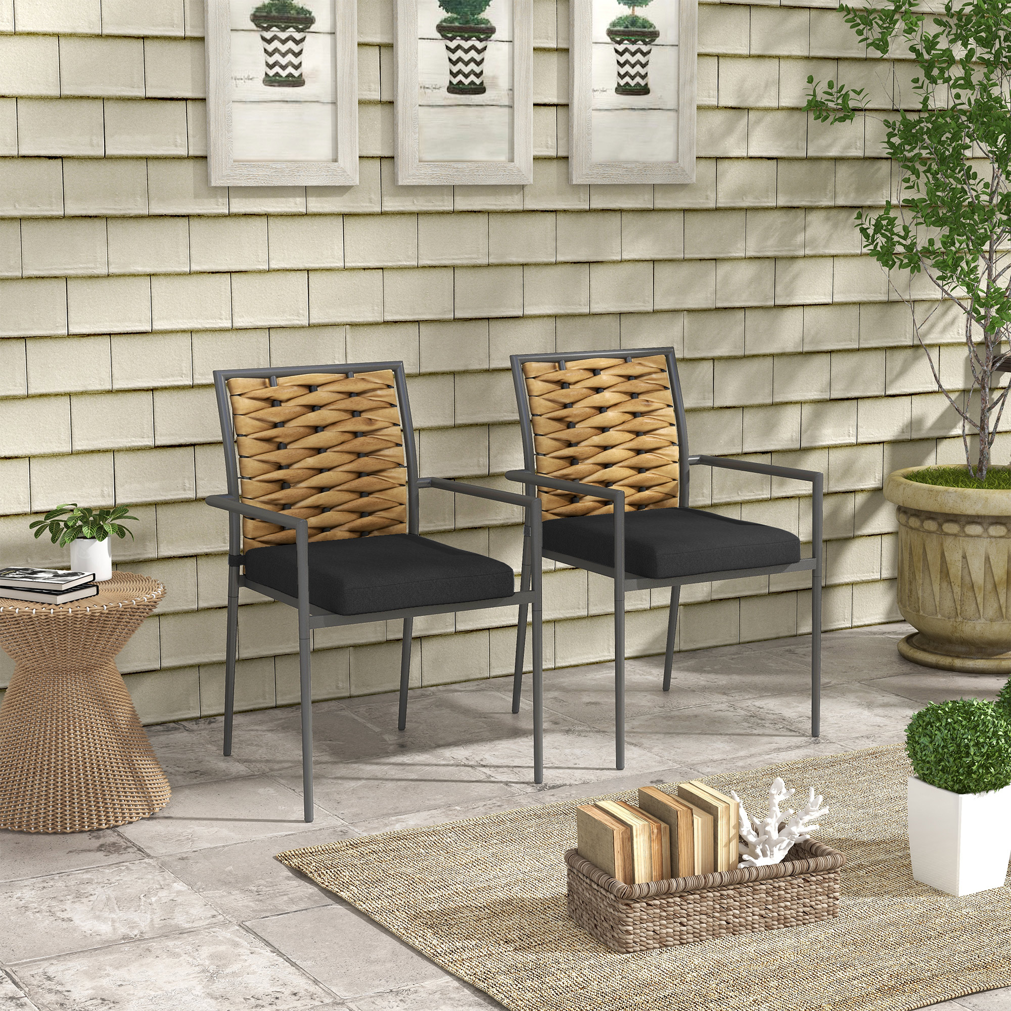 Zwei Stühle auf einer Terrasse. Die Stühle haben gewebte Rückenlehnen und schwarze Kissen.