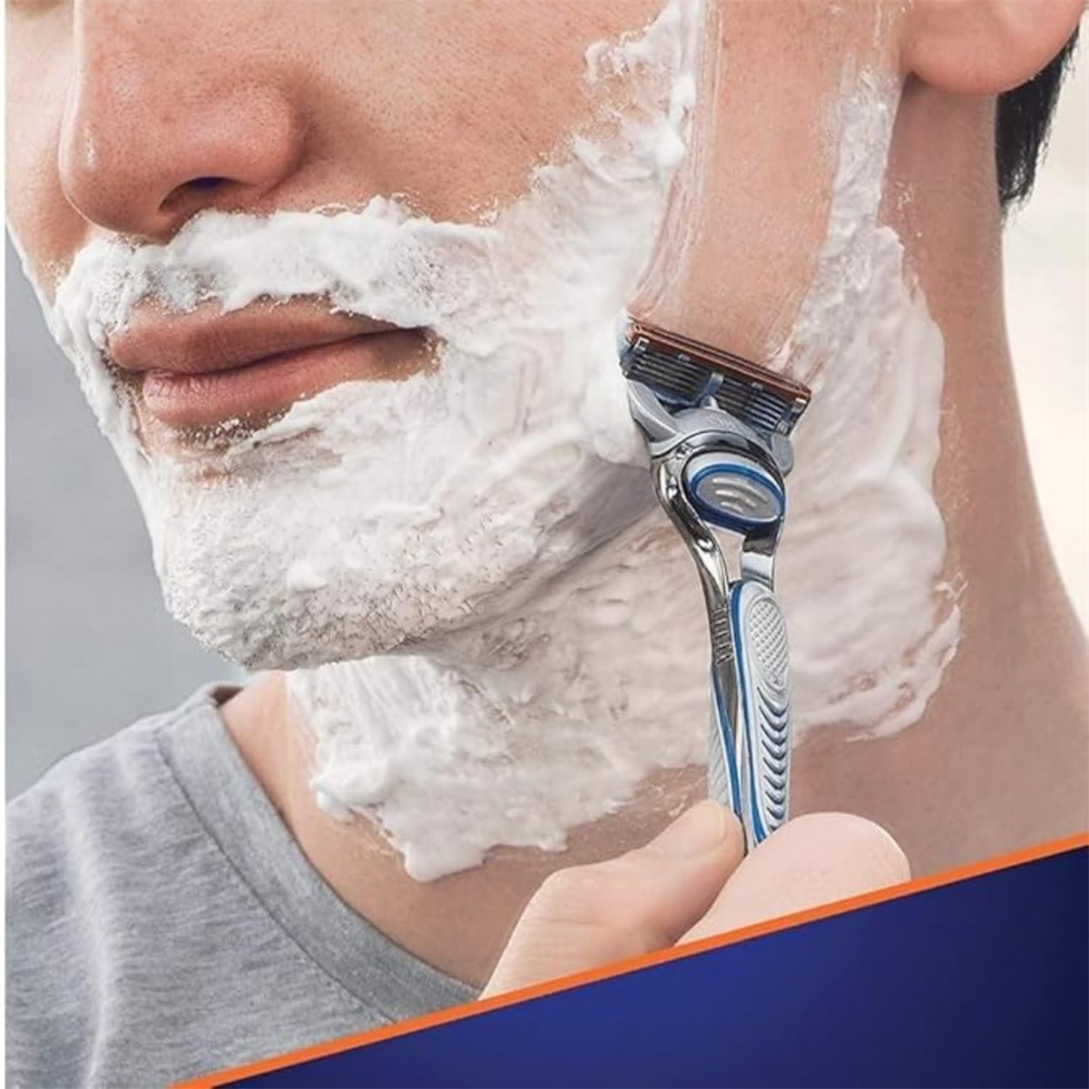 Mann rasiert sich mit einem Rasierer, bedeckt mit Rasiercreme.