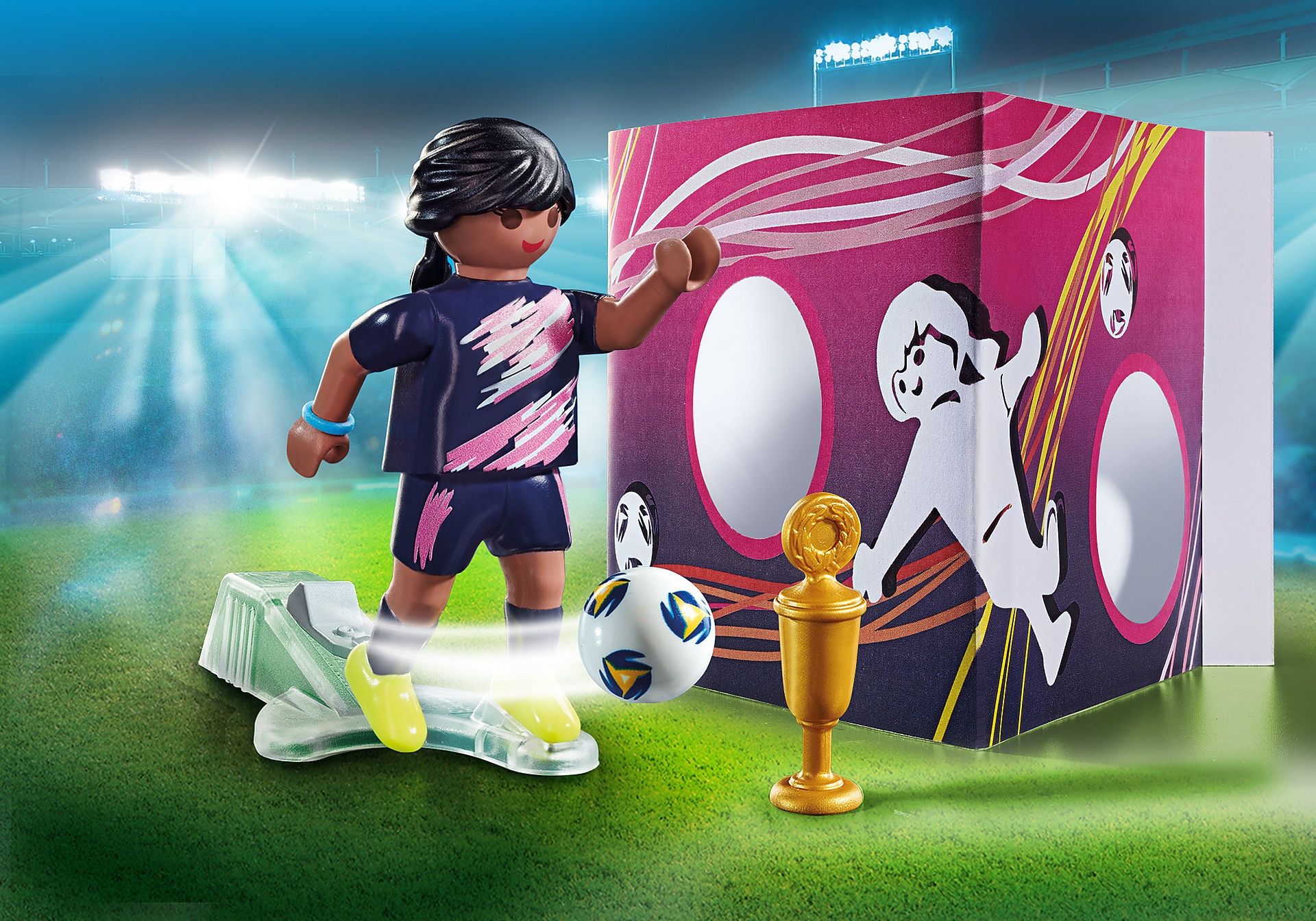 Playmobil scene: soccer player kicking a ball towards a goal. Background is a stadium.