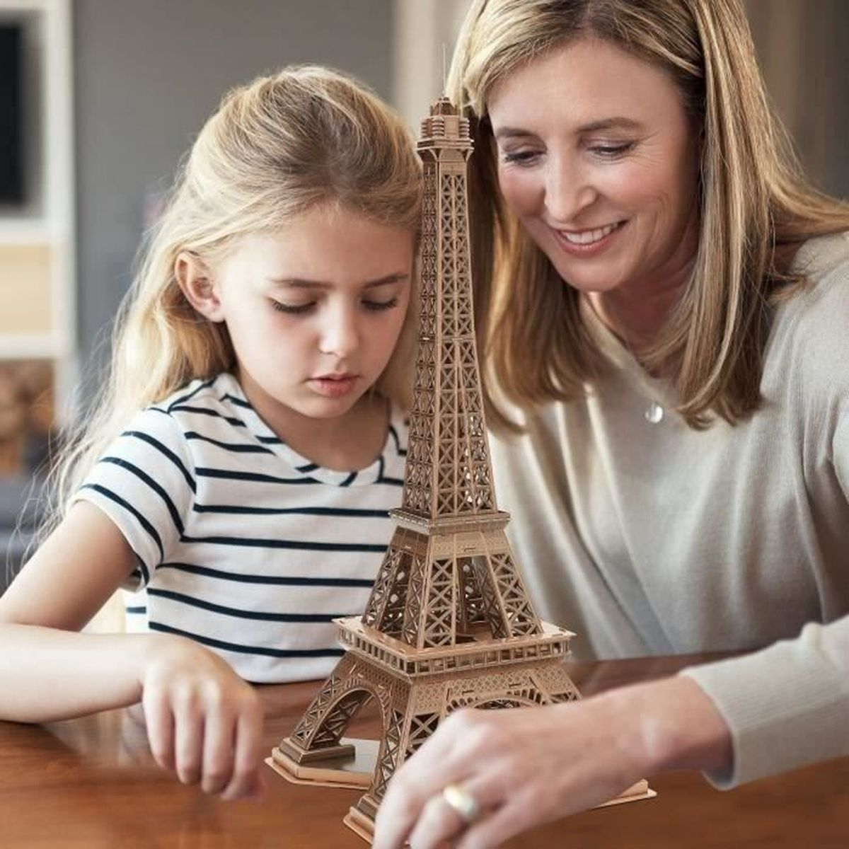 Frau und Mädchen bauen Eiffelturm-Modell zusammen.