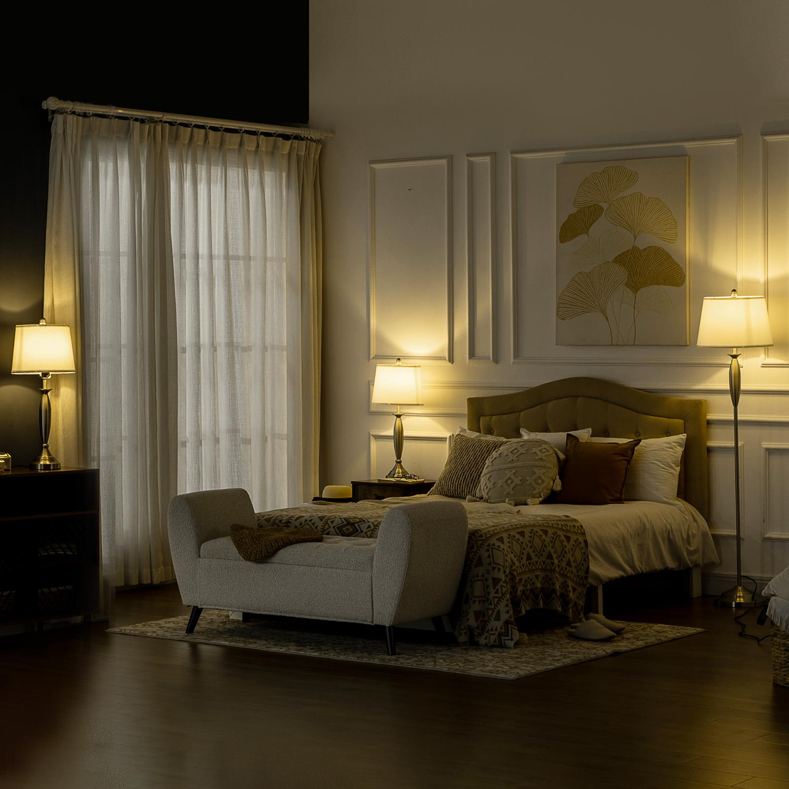 Schlafzimmer mit Bett, Lampen und einer Bank. Der Raum hat eine warme, einladende Atmosphäre.
