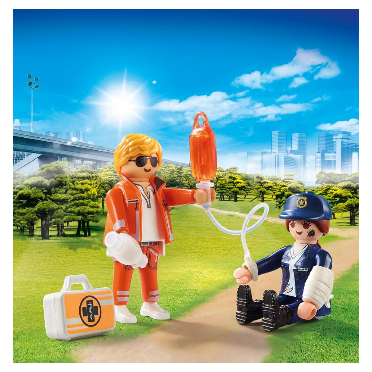 Playmobil paramedici scène met twee figuren, een gewonde. Blauwe lucht en groen landschap op de achtergrond.