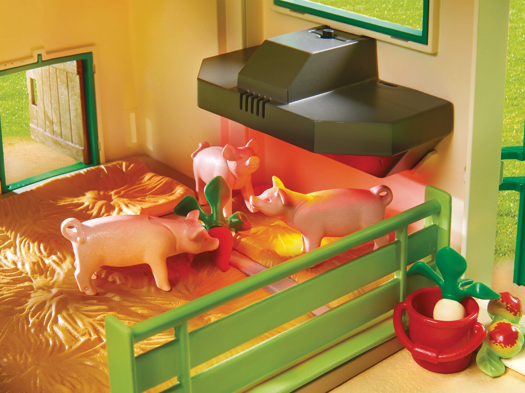 Scena Playmobil z świniami w zagrodzie ze sianem, zielonym płotem i lampą grzewczą. Czerwone rzodkwie w pobliżu.