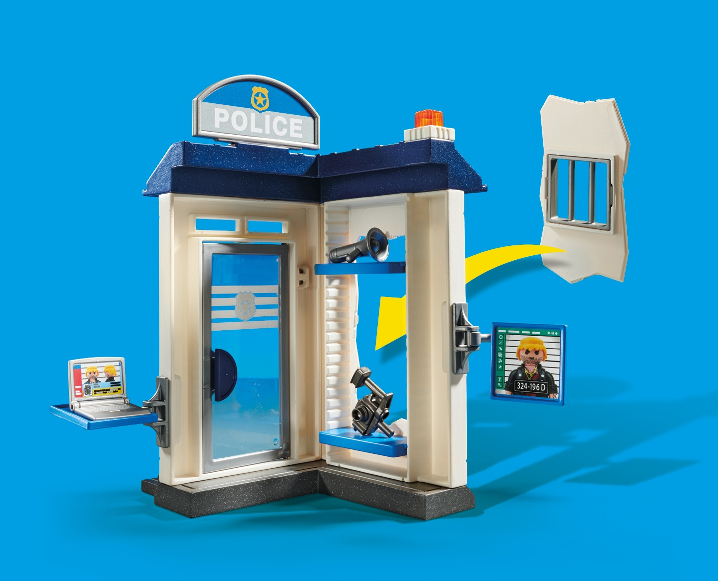 Comisaría de policía Playmobil con figuras, ordenador y celda. El fondo es un paisaje nocturno urbano.