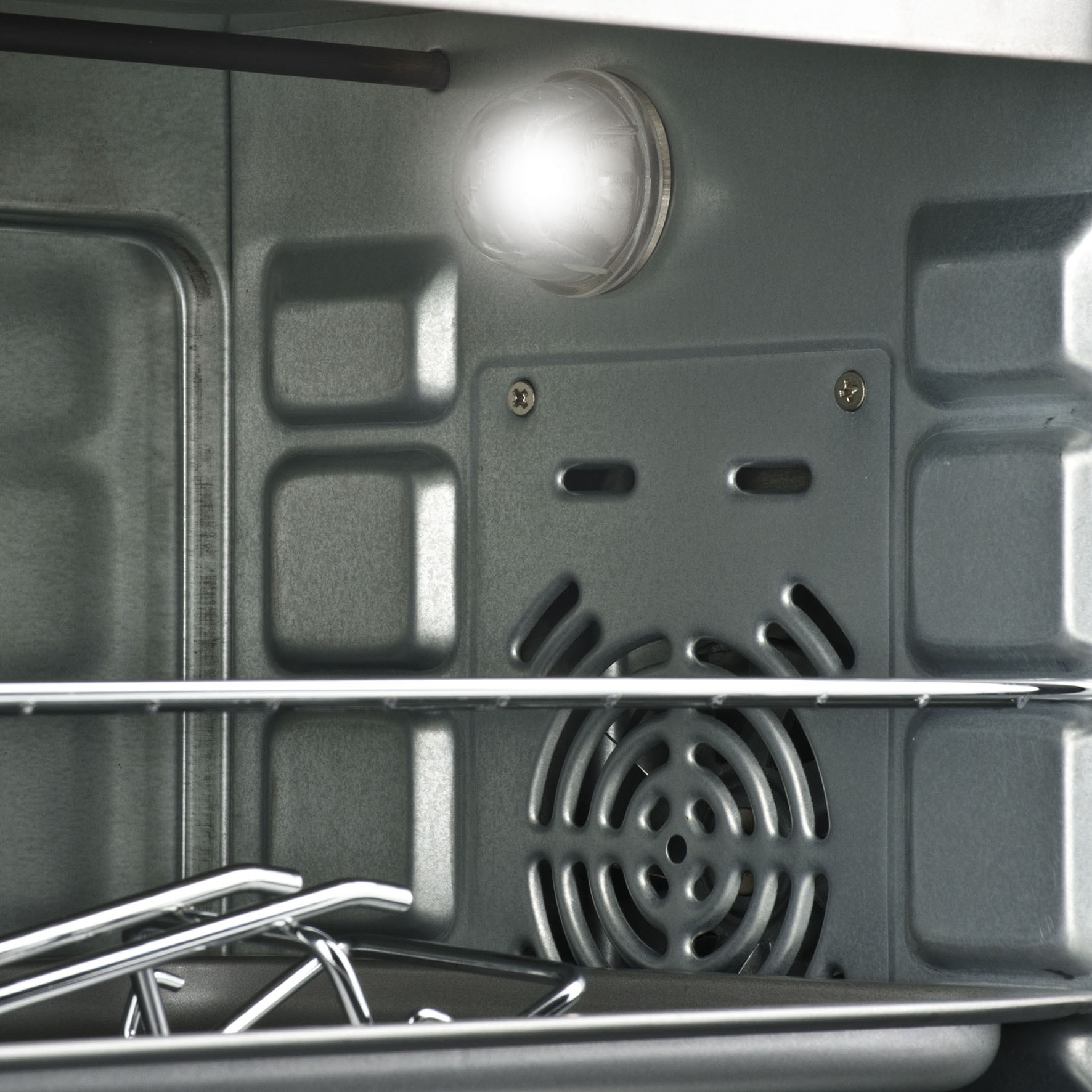 Wnętrze piekarnika ze światłem, wentylatorem i widocznymi rusztami.