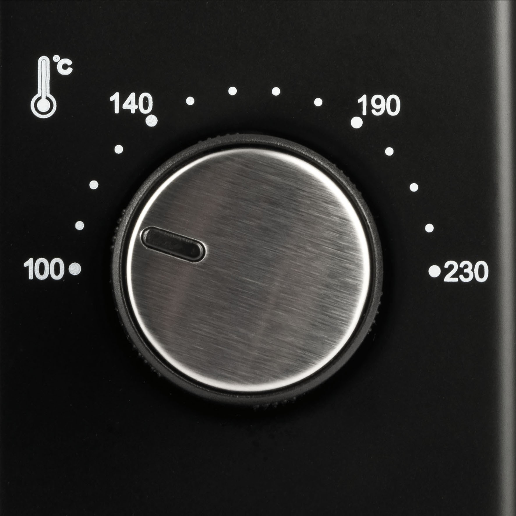 Pokrętło regulacji temperatury piekarnika. Czarne tło, białe cyfry, srebrne pokrętło.