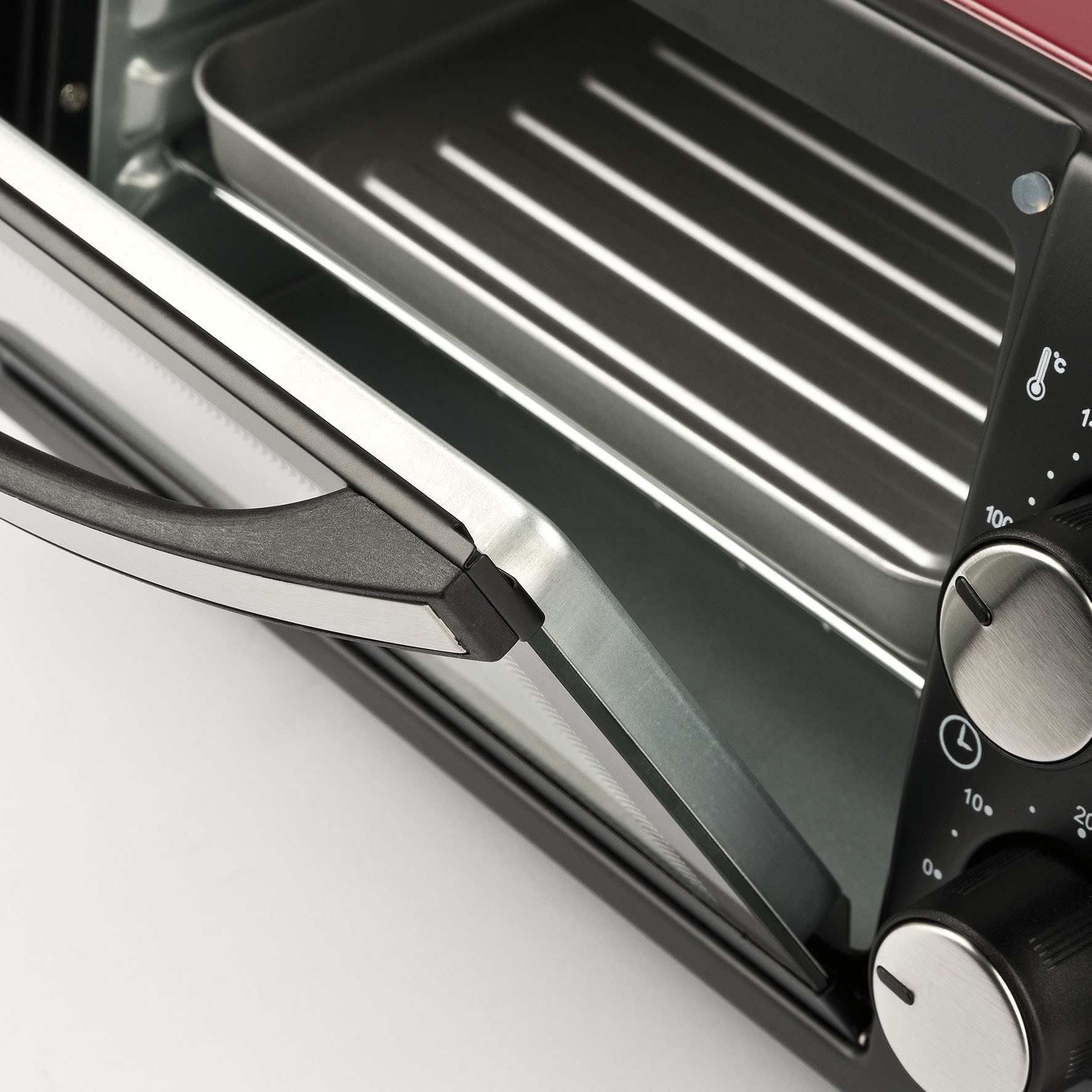 Wnętrze piekarnika z otwartymi drzwiami. Srebrne i czerwone. Białe tło.