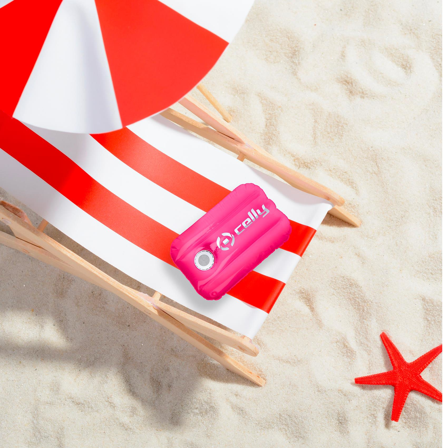 Scena na plaży z czerwono-białym krzesłem w paski, parasolem i różową poduszką.