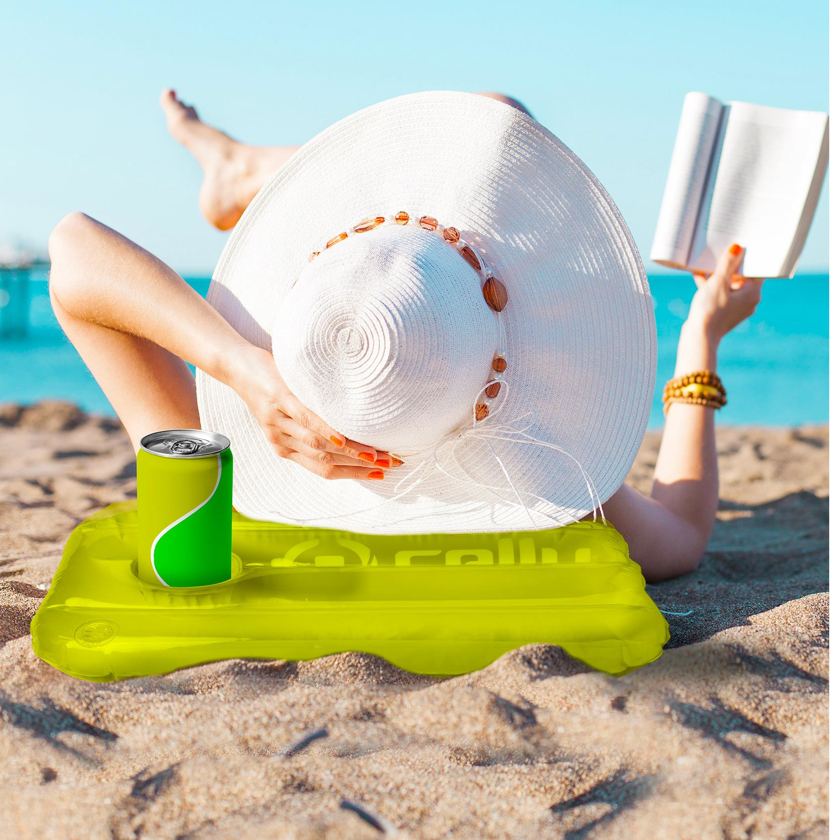 Una persona che si rilassa su una spiaggia con un libro, un drink e un galleggiante giallo. C'è un cappello bianco.