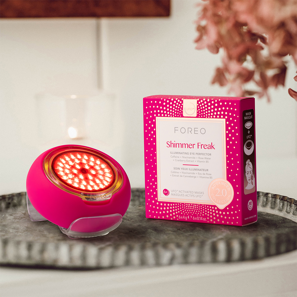 A pink face device and a pink box on a tray. The device has red lights.