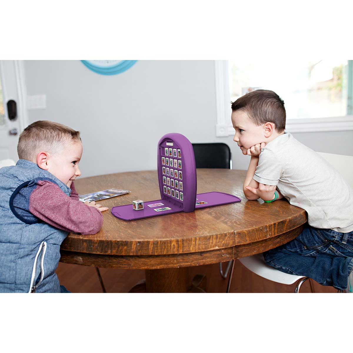Zwei junge Jungen spielen ein Spiel. Ein lila Spielbrett ist in der Mitte.