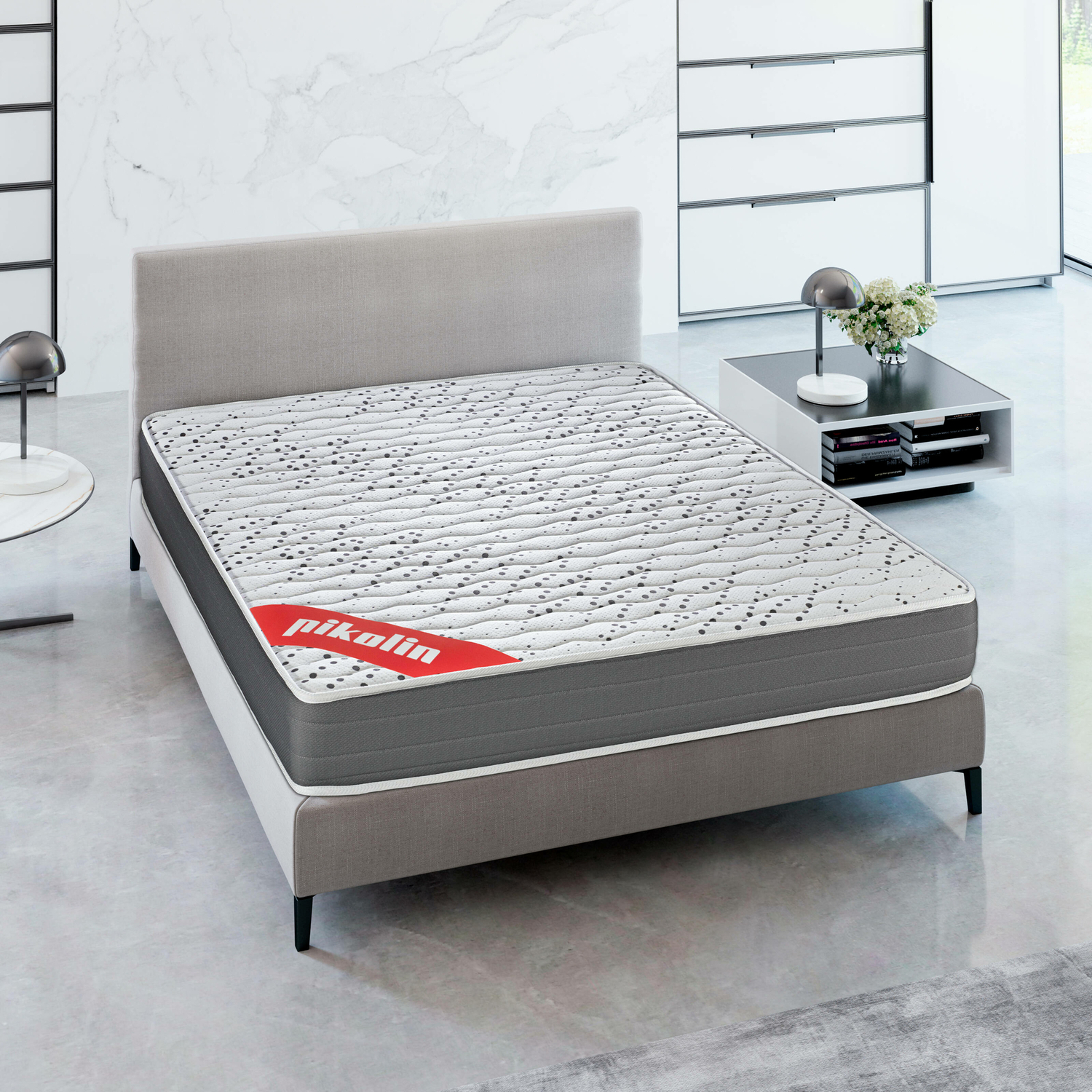 Una cama con colchón gris, cabecero gris y base blanca, en un ambiente de habitación.