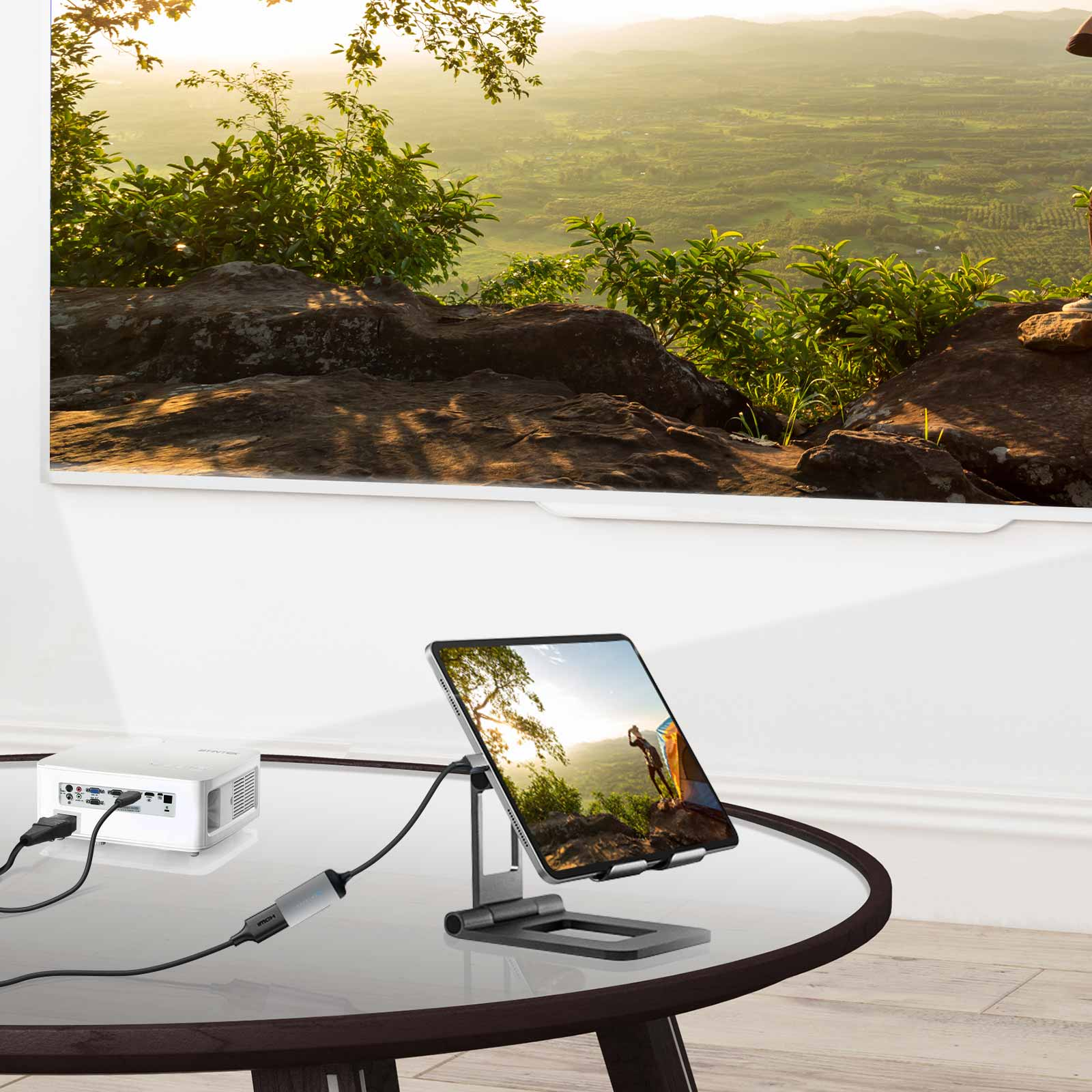 Tablet auf Ständer, verbunden mit einem Projektor und einem großen Fernsehbildschirm. Grüne Landschaft im Hintergrund.