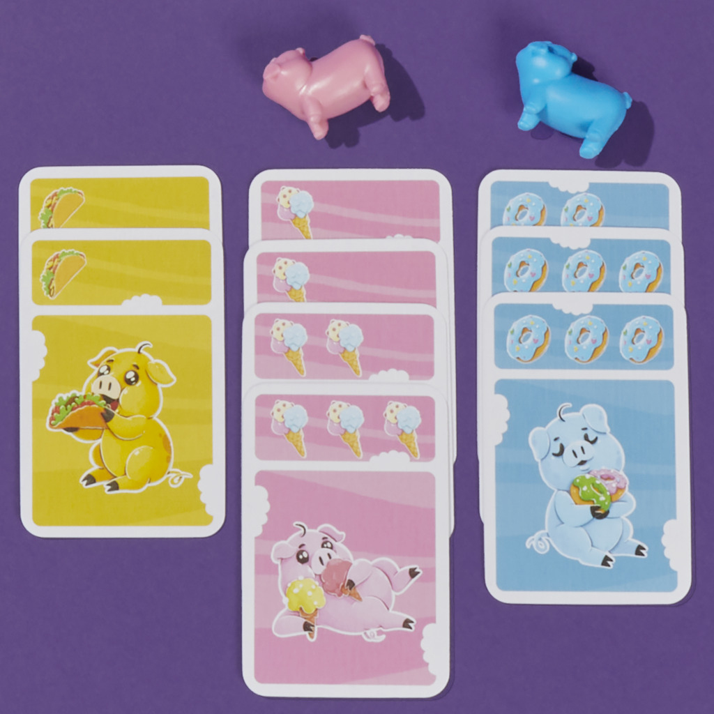 Schweine-Brettspiel mit Karten mit Essen und Schweinen, zwei Spielzeugschweine oben.
