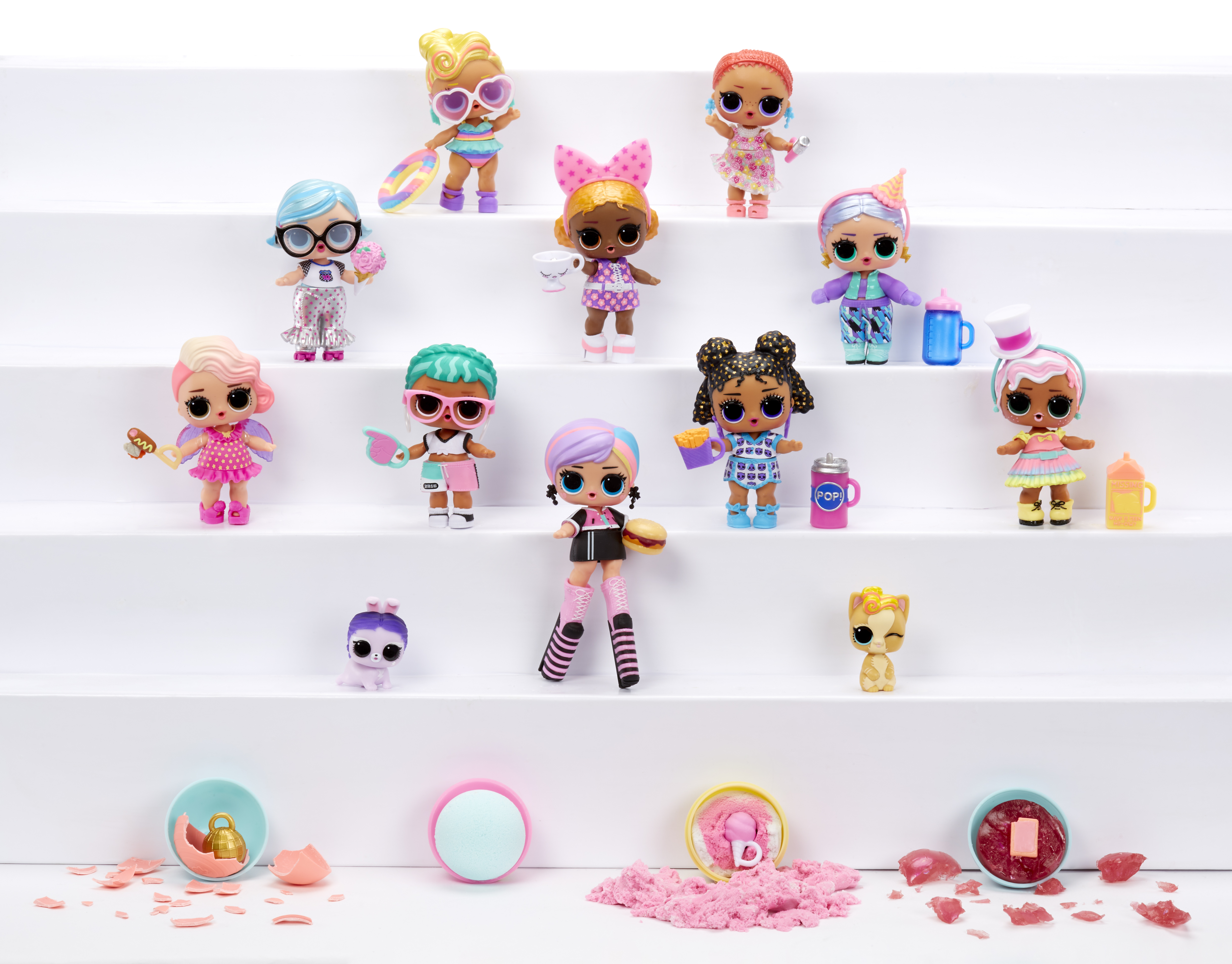 Lalki na białych, piętrowych półkach. Różne lalki z akcesoriami, w tym okularami przeciwsłonecznymi.