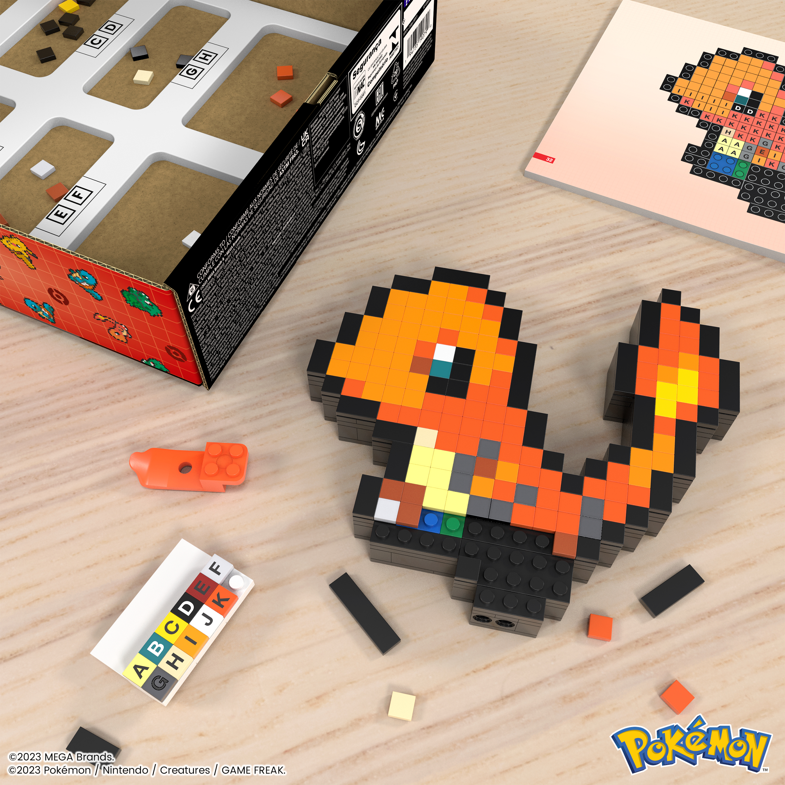 Un jouet Charmander en briques et d'autres pièces Lego sont sur une table en bois avec une boîte.