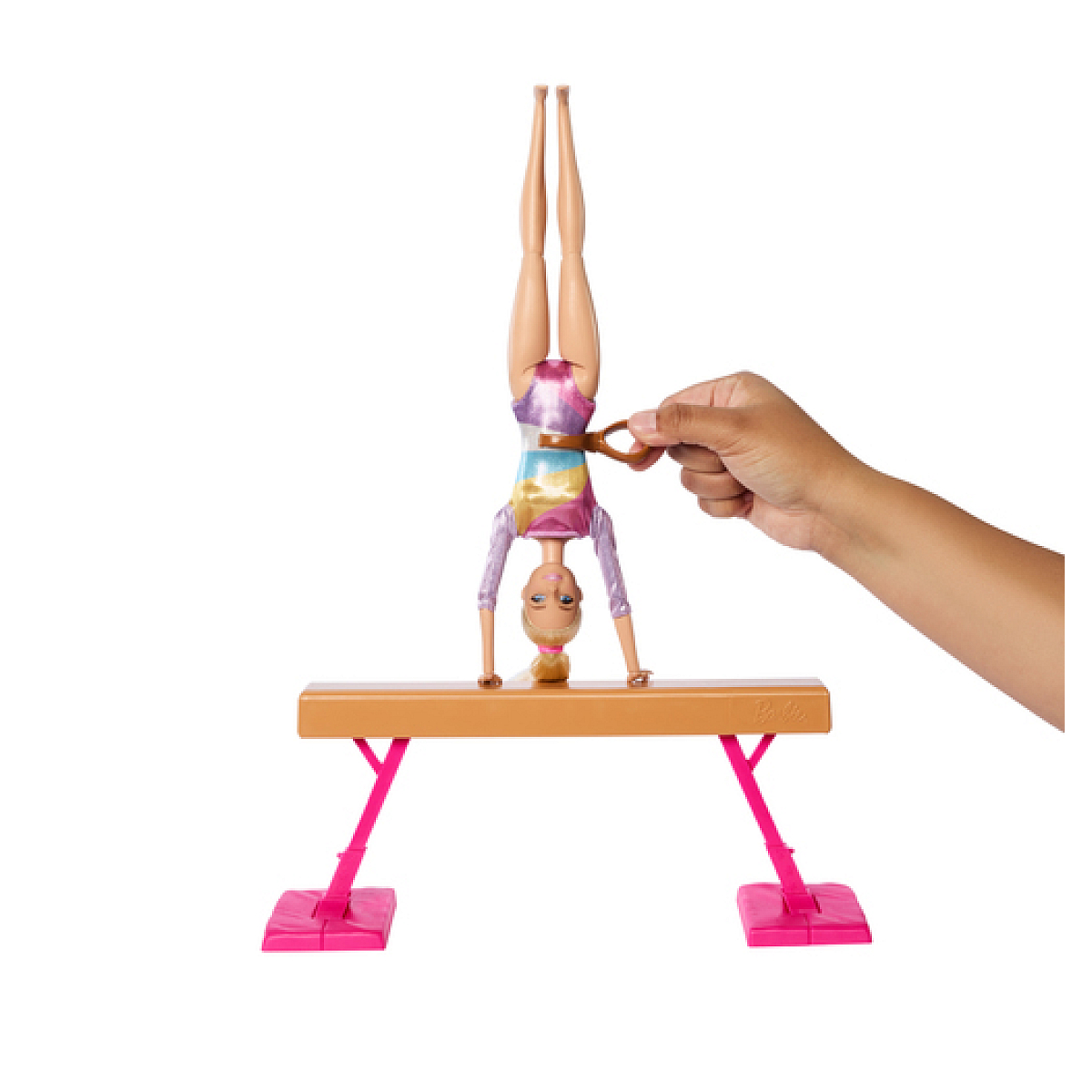 Lalka Barbie w pozie gimnastycznej na równoważni, trzymana przez rękę.