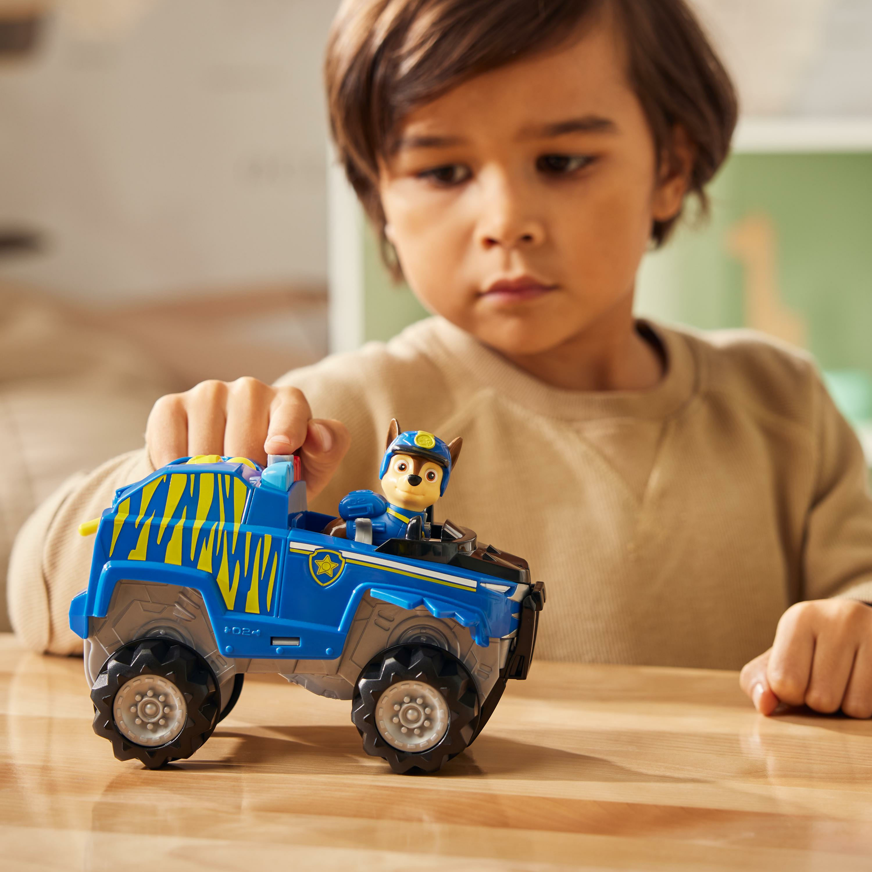 Ein Kind spielt mit einem blauen Paw Patrol Spielzeug-Truck mit einer Chase-Figur.