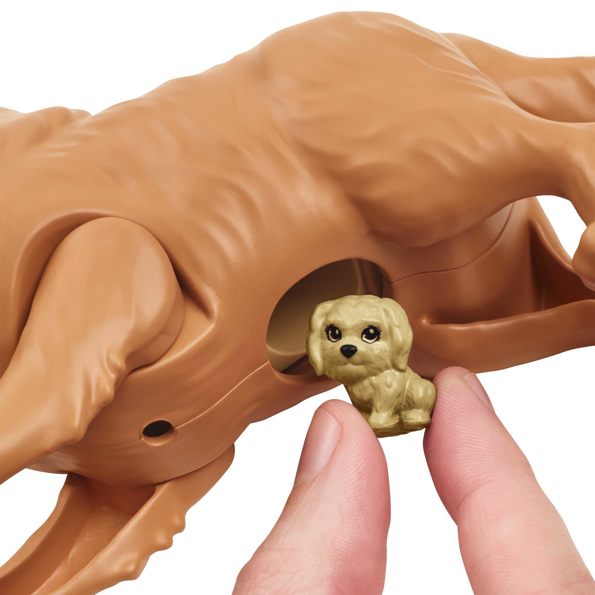 Mały szczeniak jest w zabawce Barbie. Zabawka jest brązowa. Ręka trzyma zabawkę.