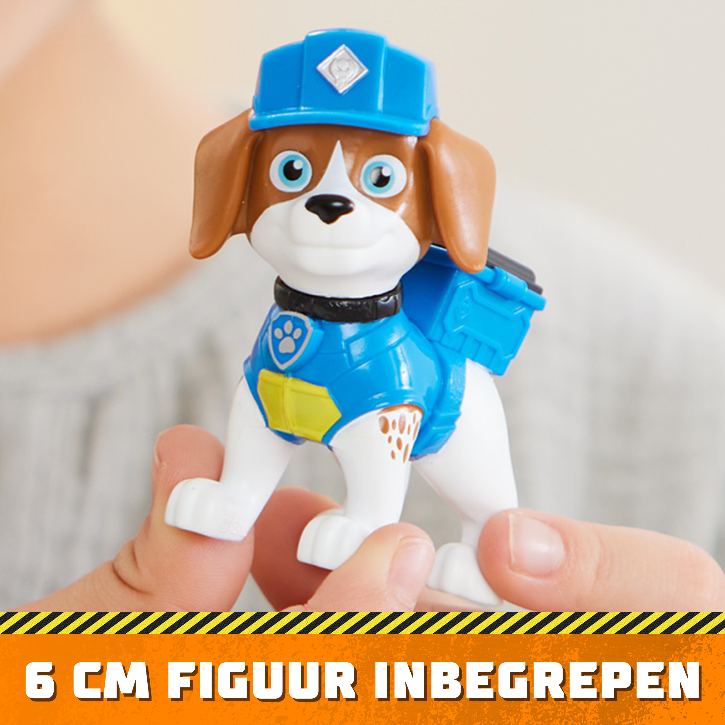 Eine Spielfigur eines Hundes in blauer Uniform, wird von Händen gehalten.