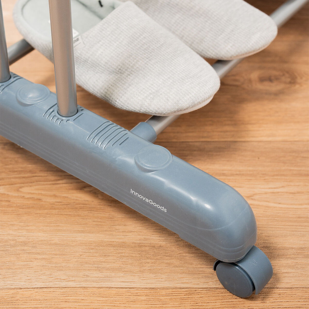 Un appendiabiti grigio InnovaGoods con pantofole grigie su un pavimento in legno.