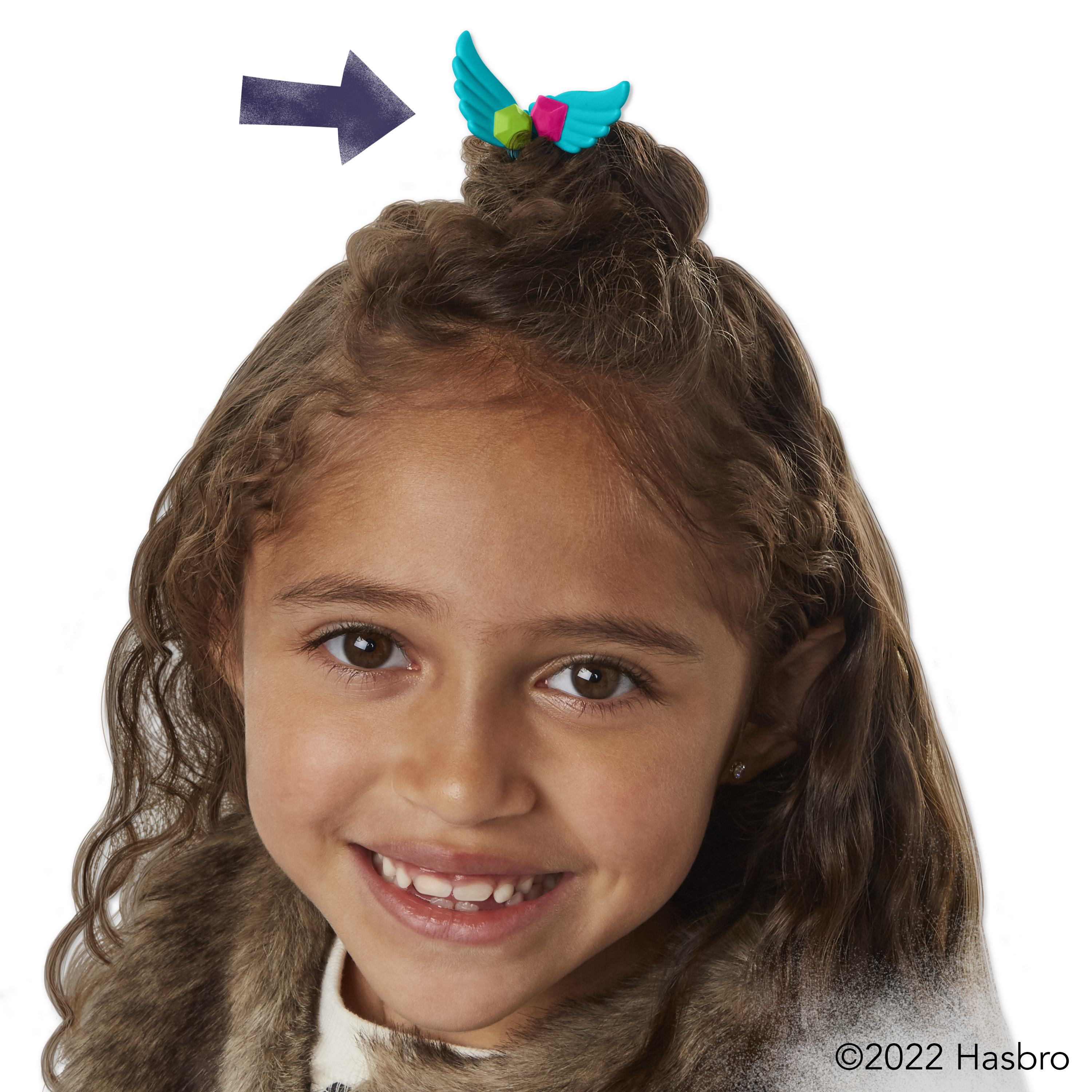Una niña con una pinza para el pelo con alas, sonriendo a la cámara.