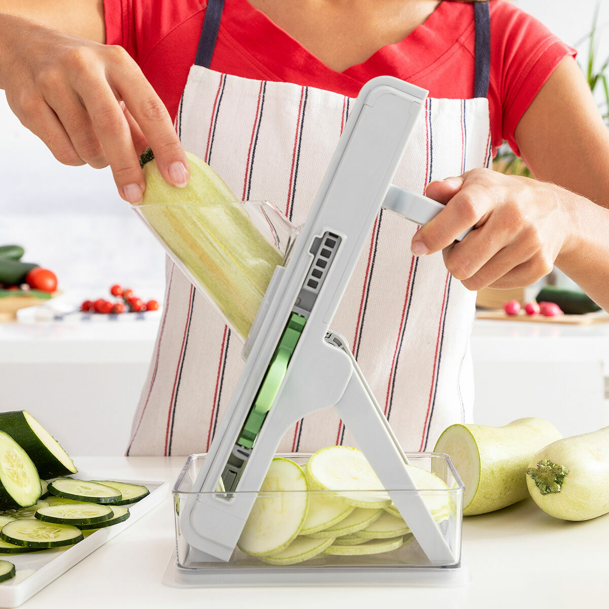 Una mujer corta un calabacín con una herramienta de cocina.