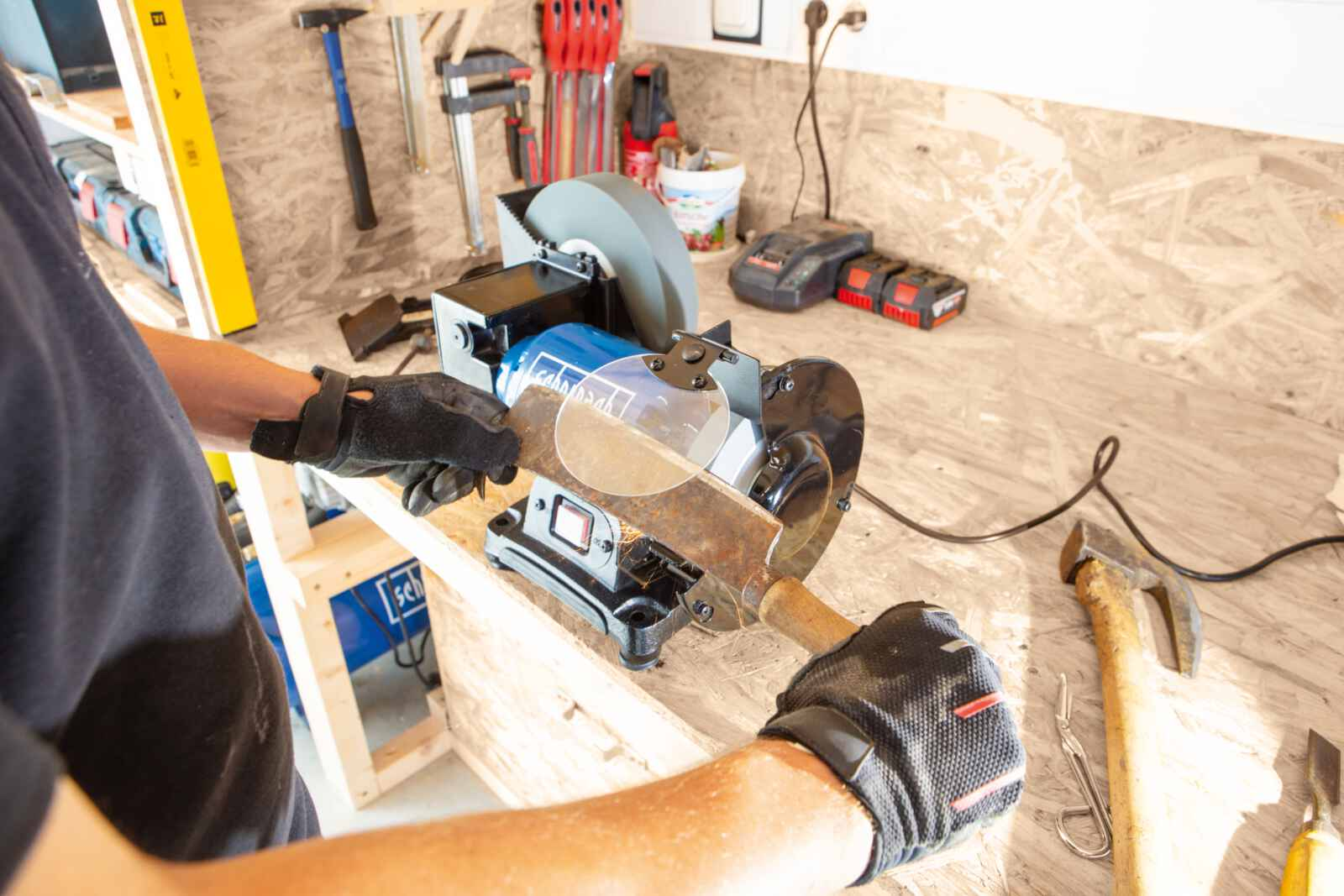 Persoon met handschoenen slijpt een mes op een slijpschijf. Houten werkbank op de achtergrond.